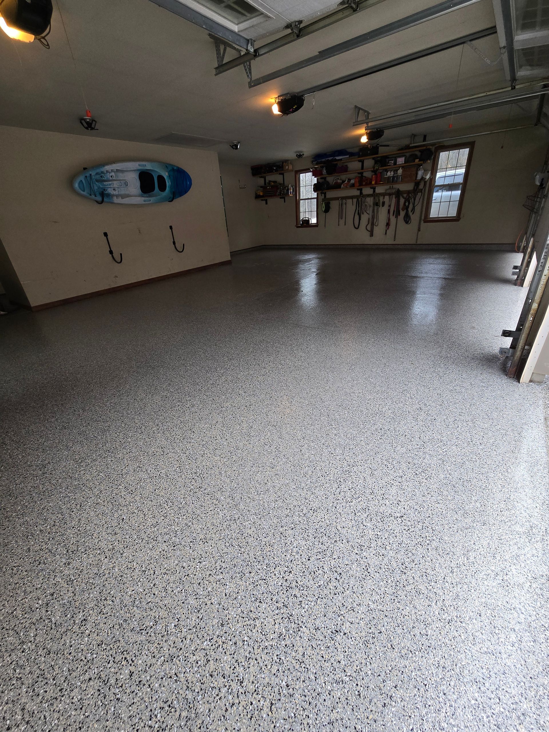 A garage with a kayak hanging on the wall and a gray floor.