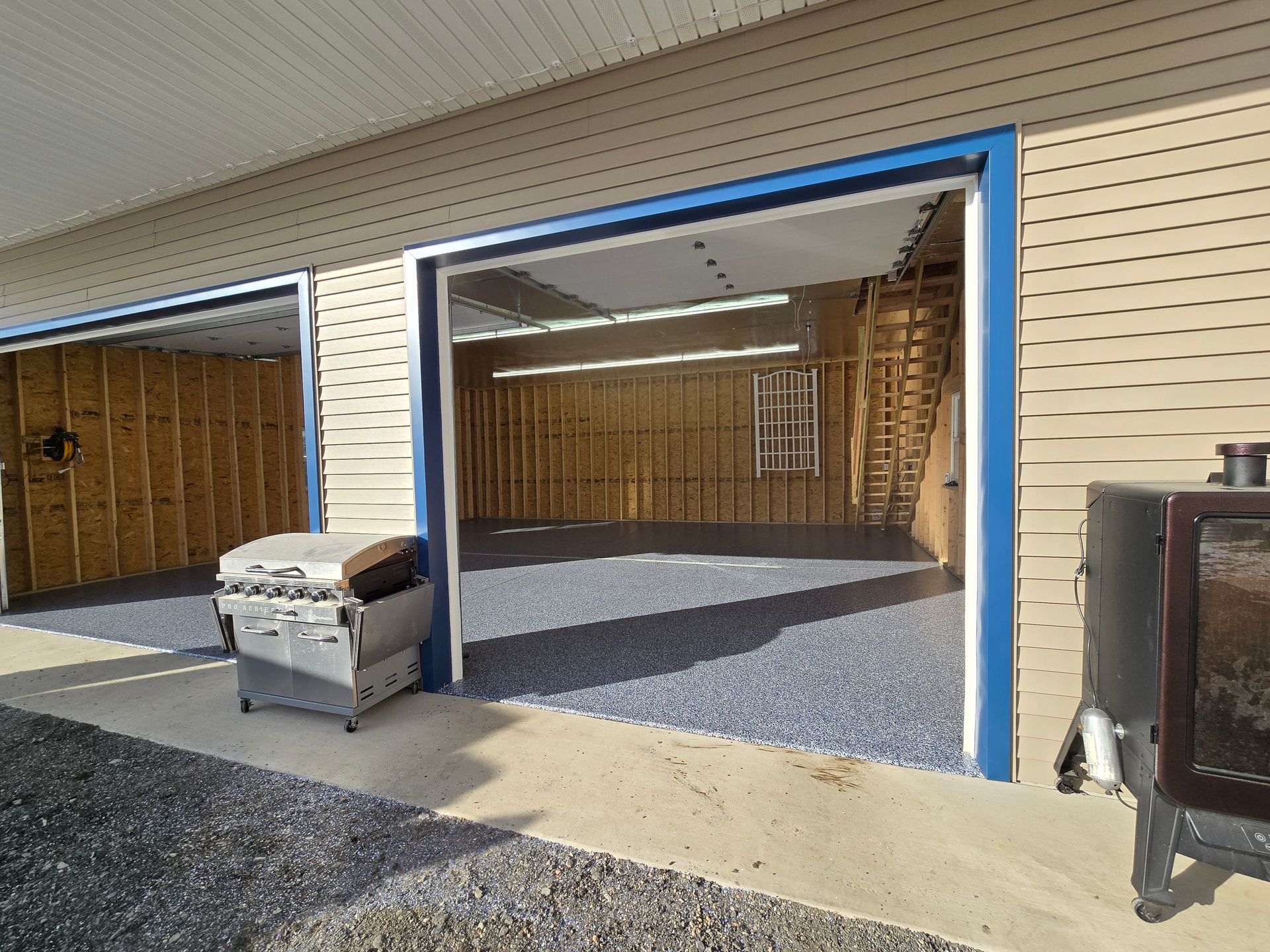 A garage with two doors open and a fireplace in the background.