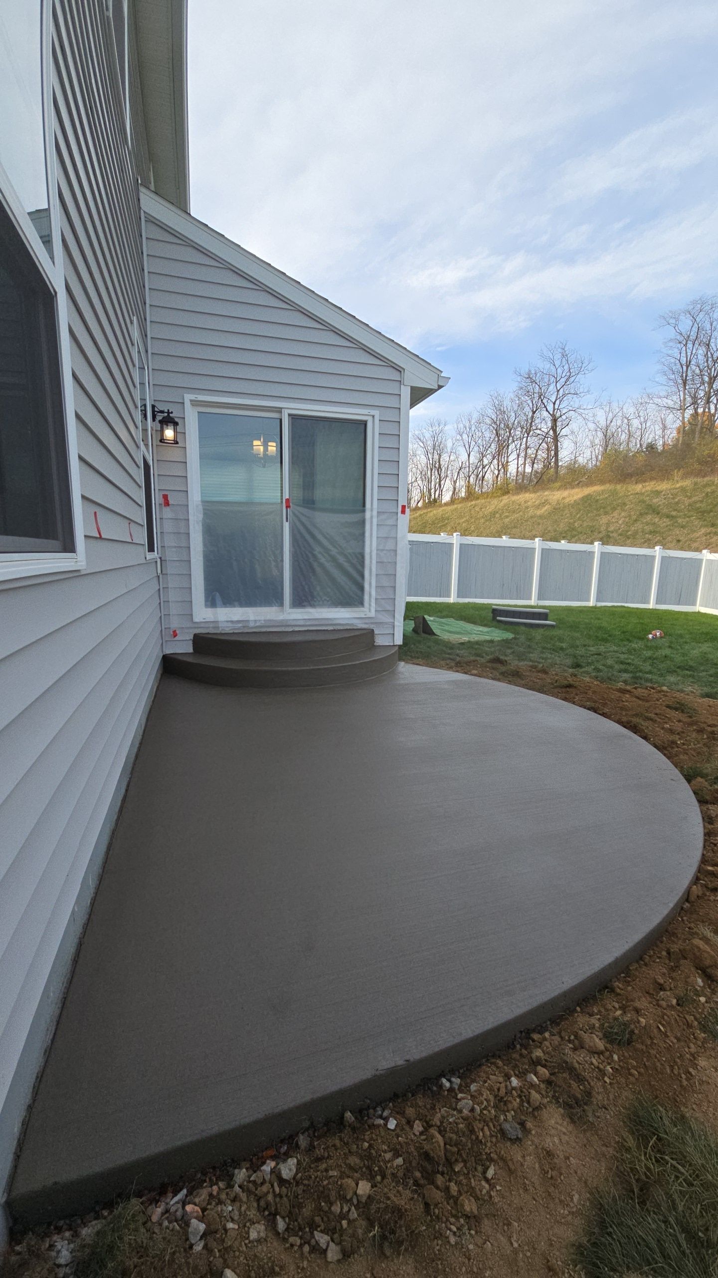 A patio with a sliding glass door in the backyard of a house.
