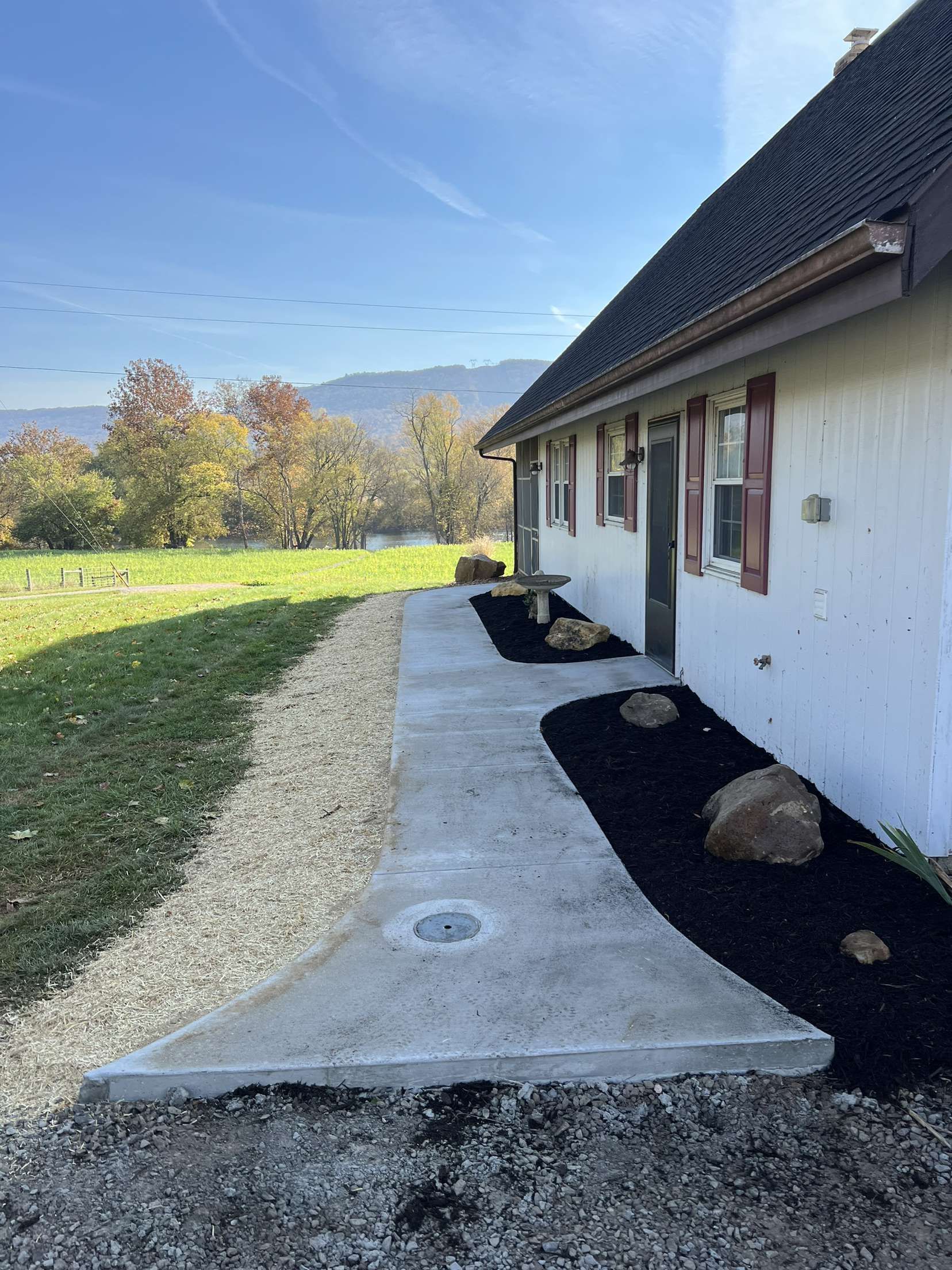 A white house with a concrete walkway leading to it.