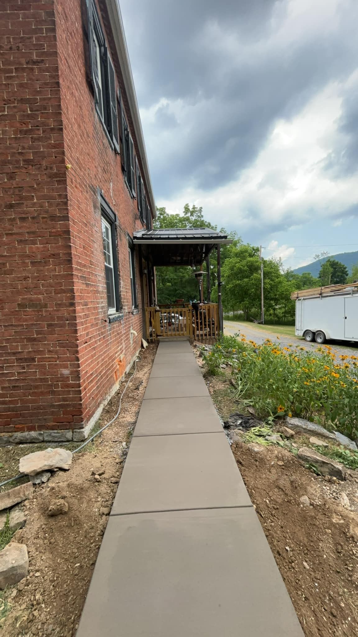 A sidewalk leading to a brick building with a porch.