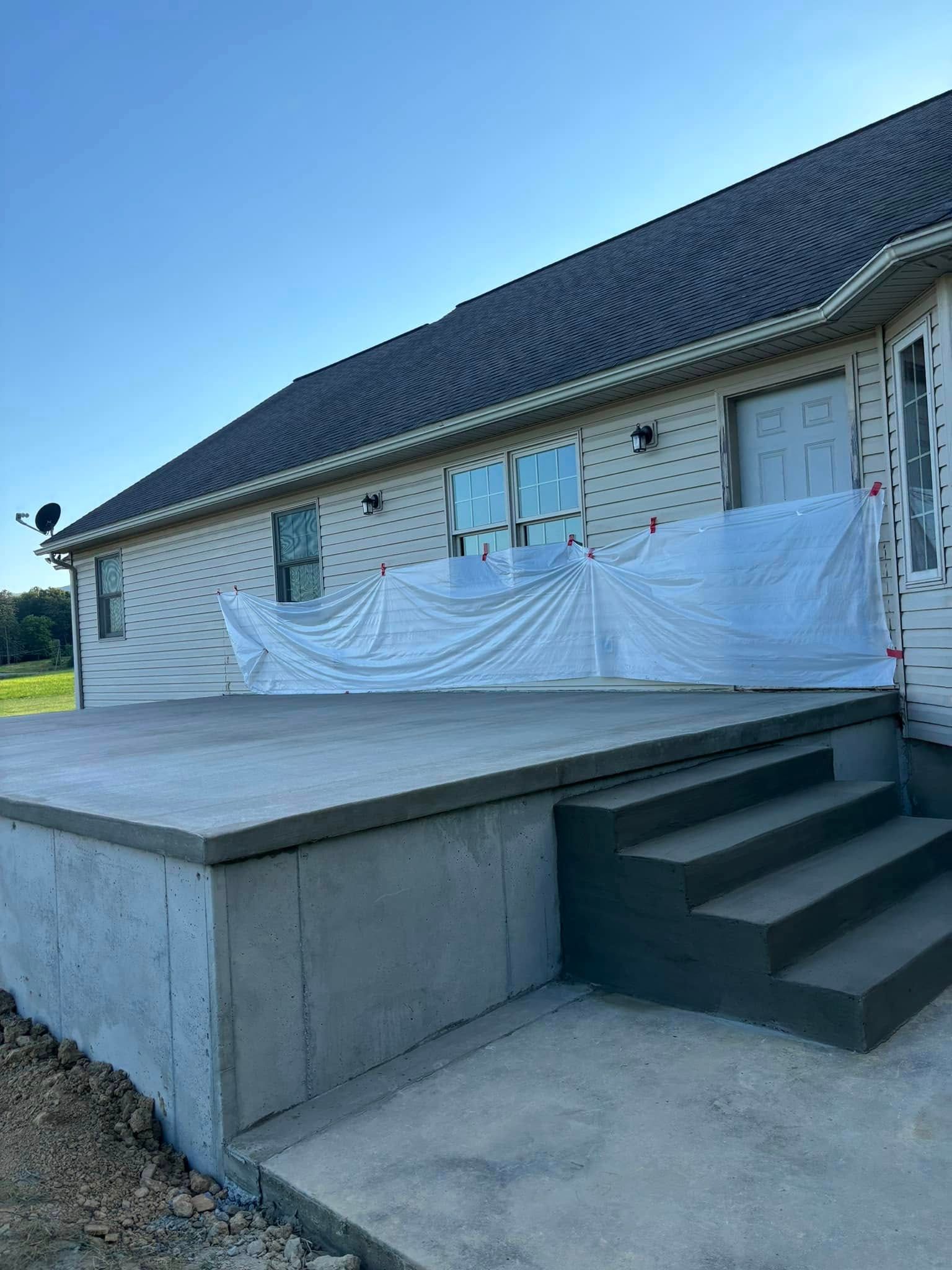 A house with a concrete deck and stairs in front of it.