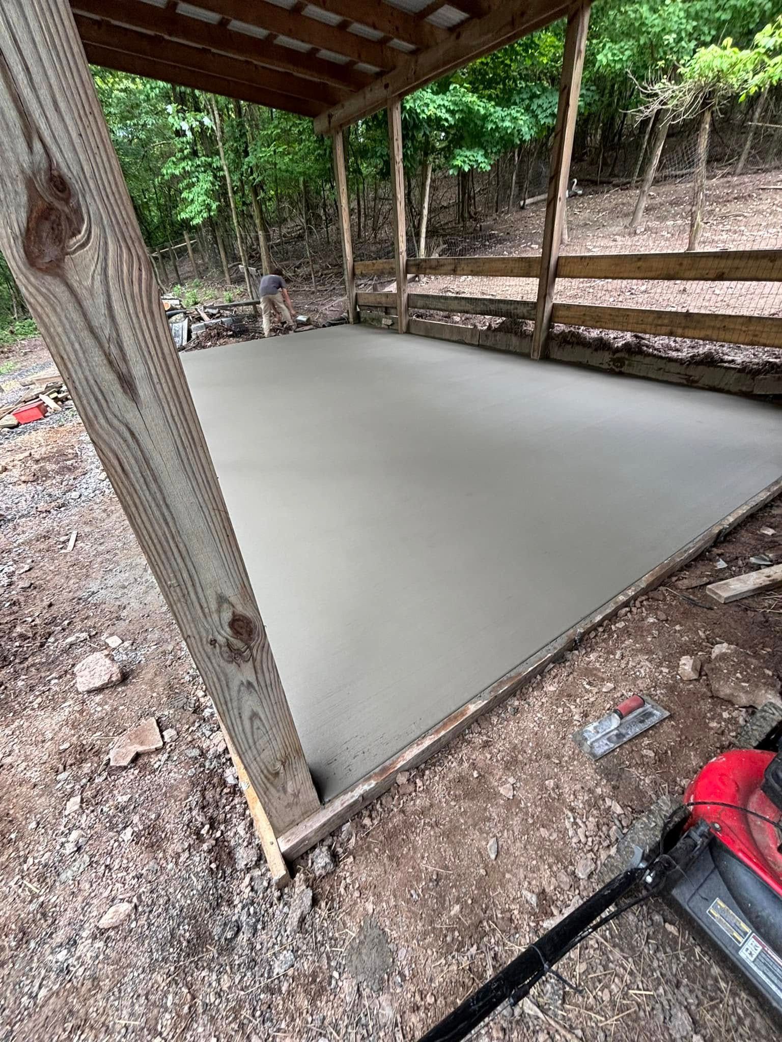 A concrete floor is being built under a wooden structure.