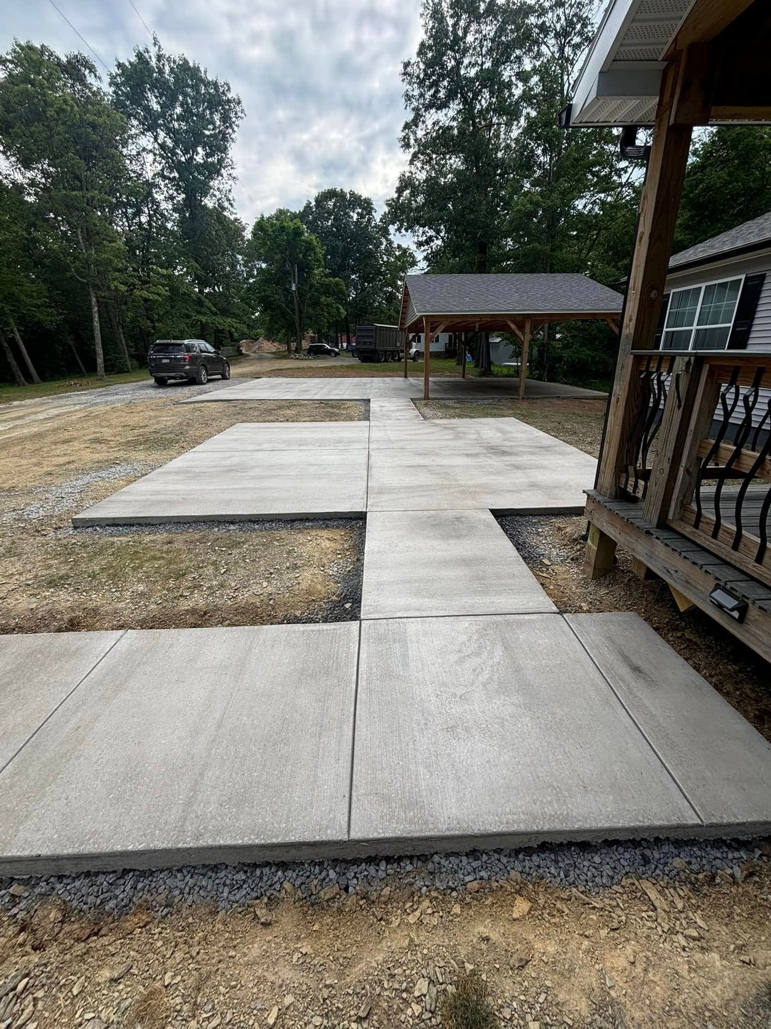 A concrete walkway is being built in a yard next to a house.