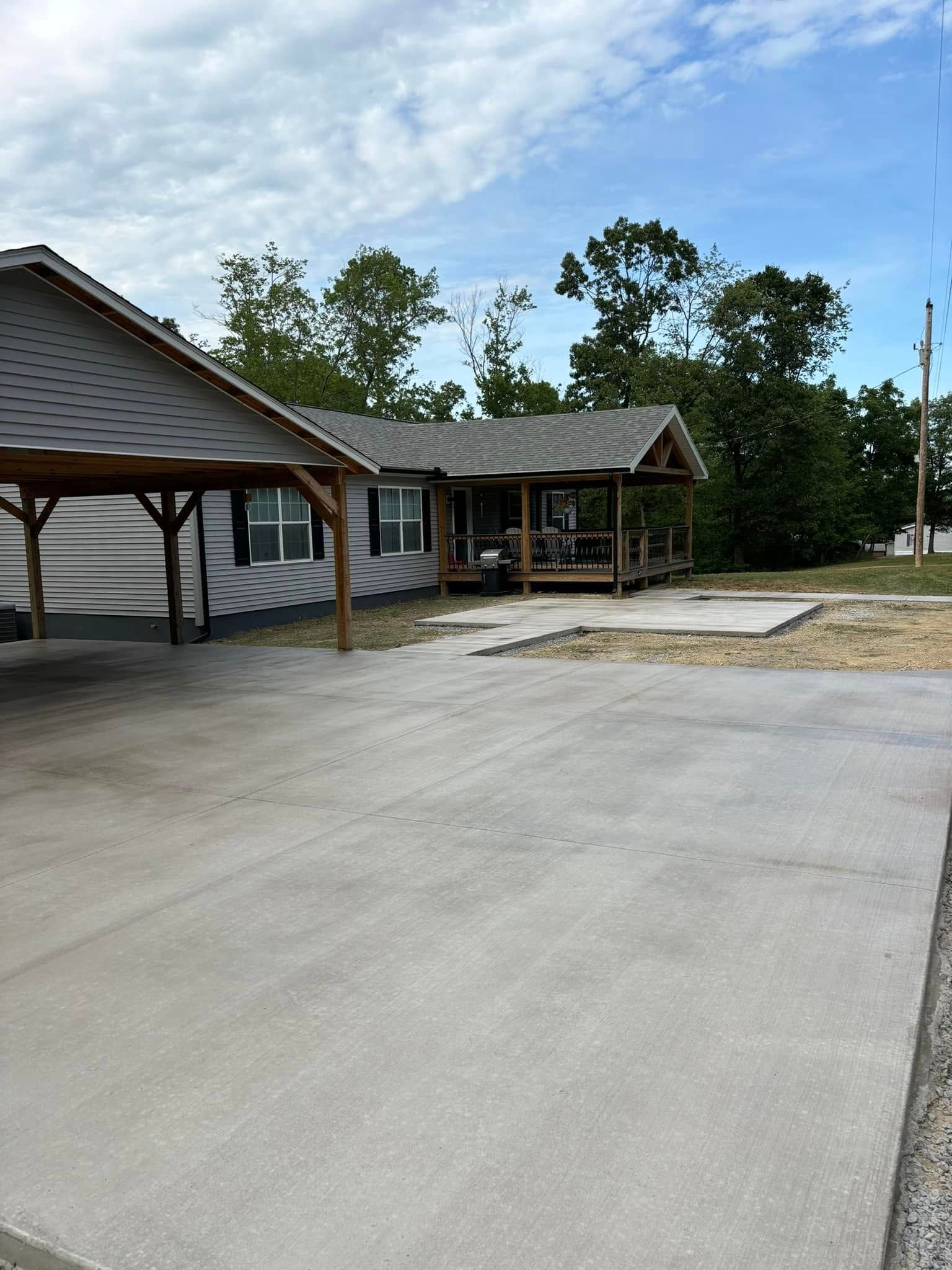 A house with a carport and a concrete driveway in front of it.