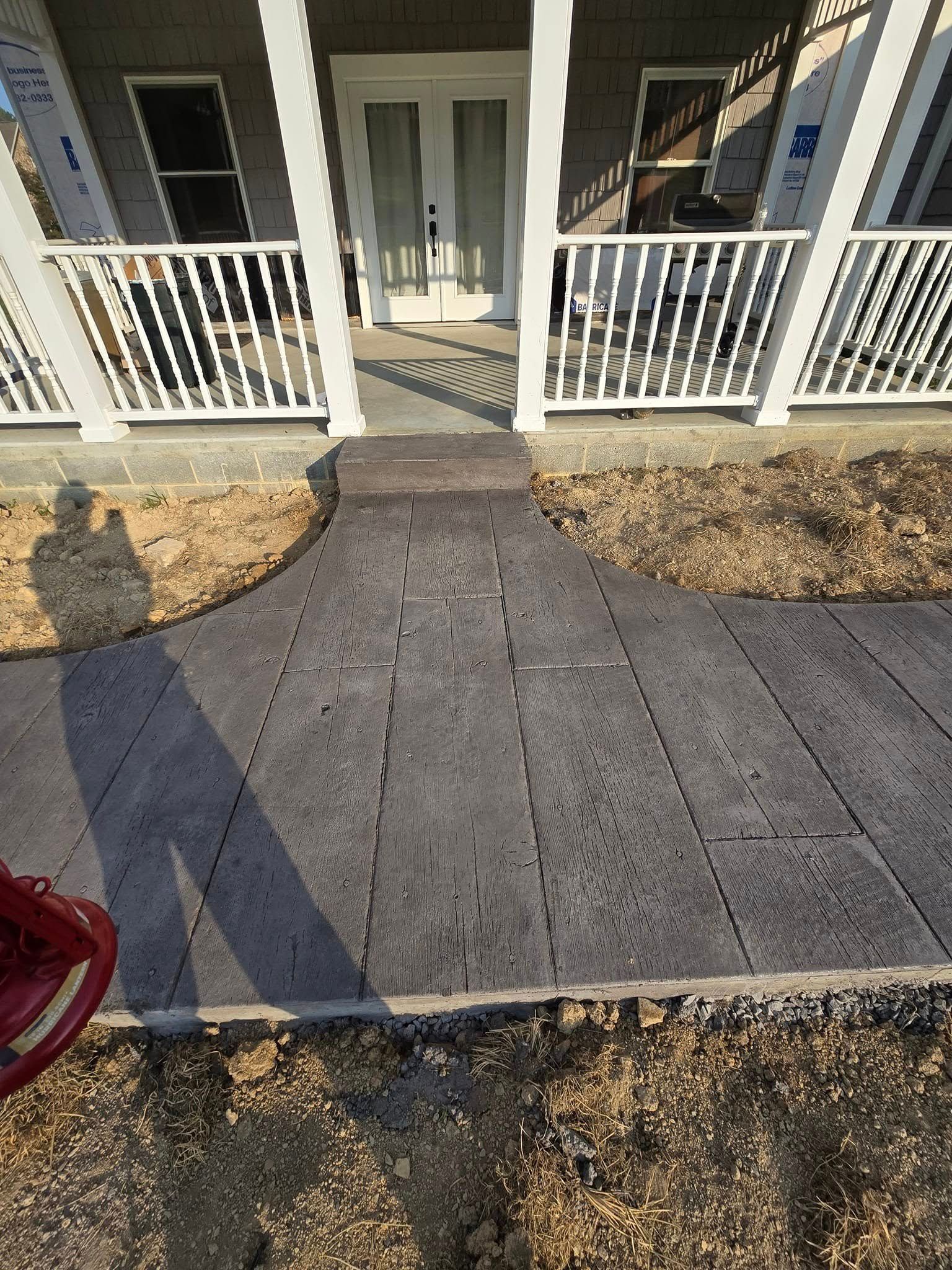 A concrete walkway leading to a porch of a house.