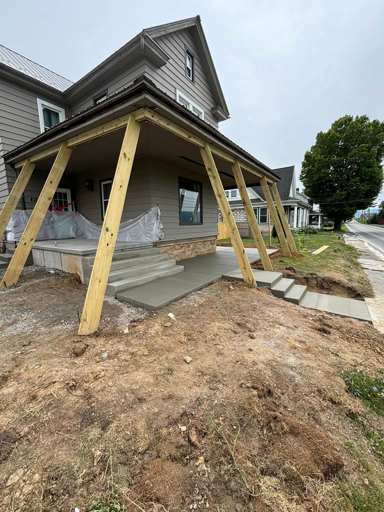 A house with a porch being built on the side of it.