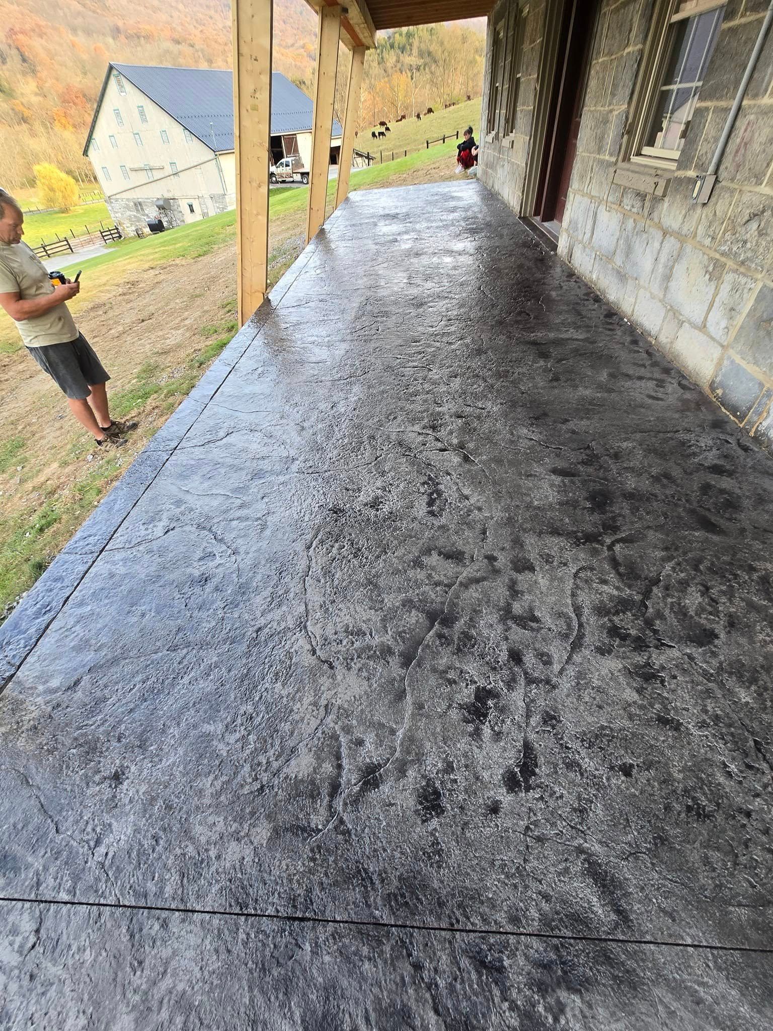 A man is standing on a concrete porch next to a building.