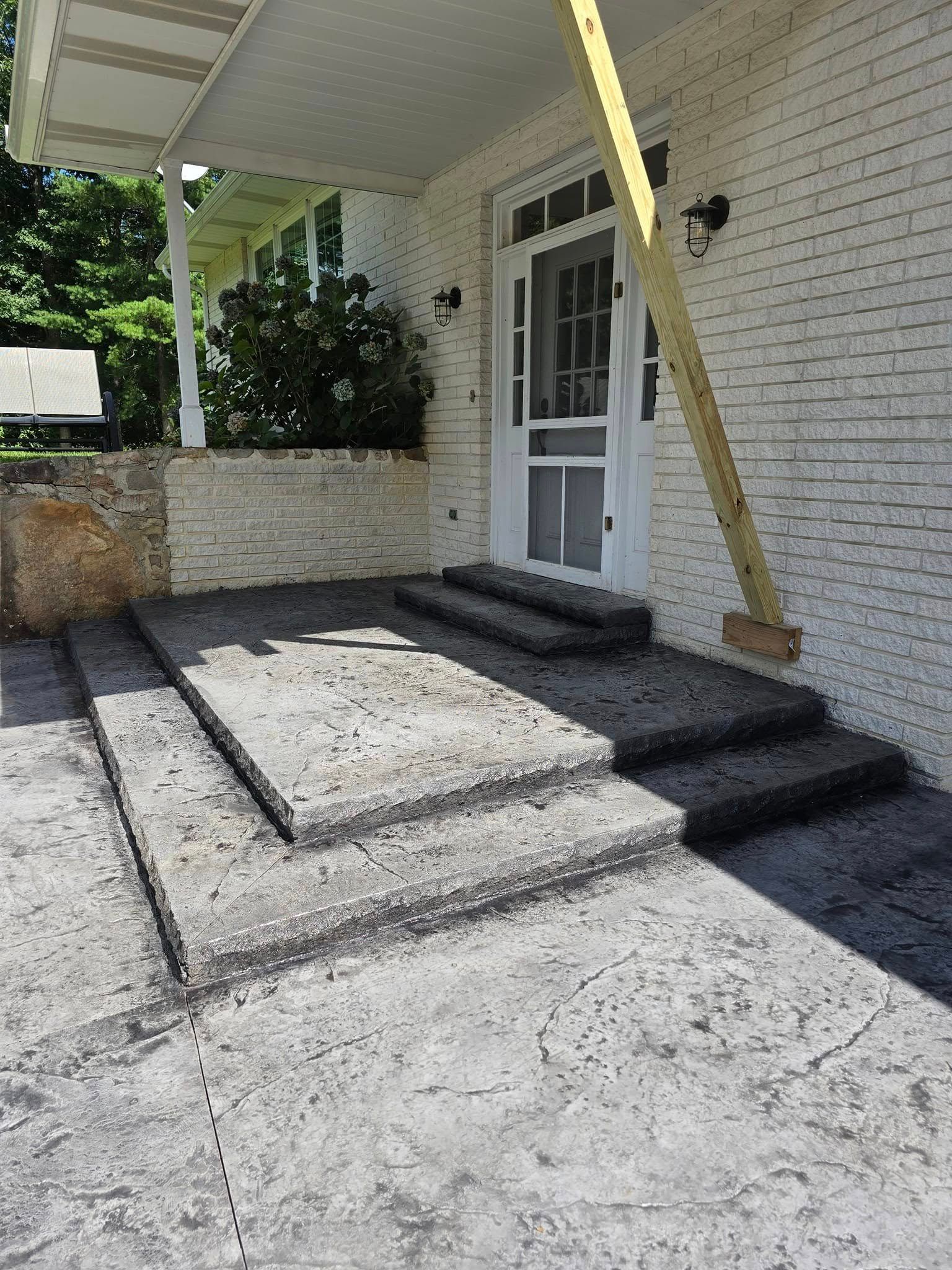 A white brick house with a porch and stairs leading up to it.