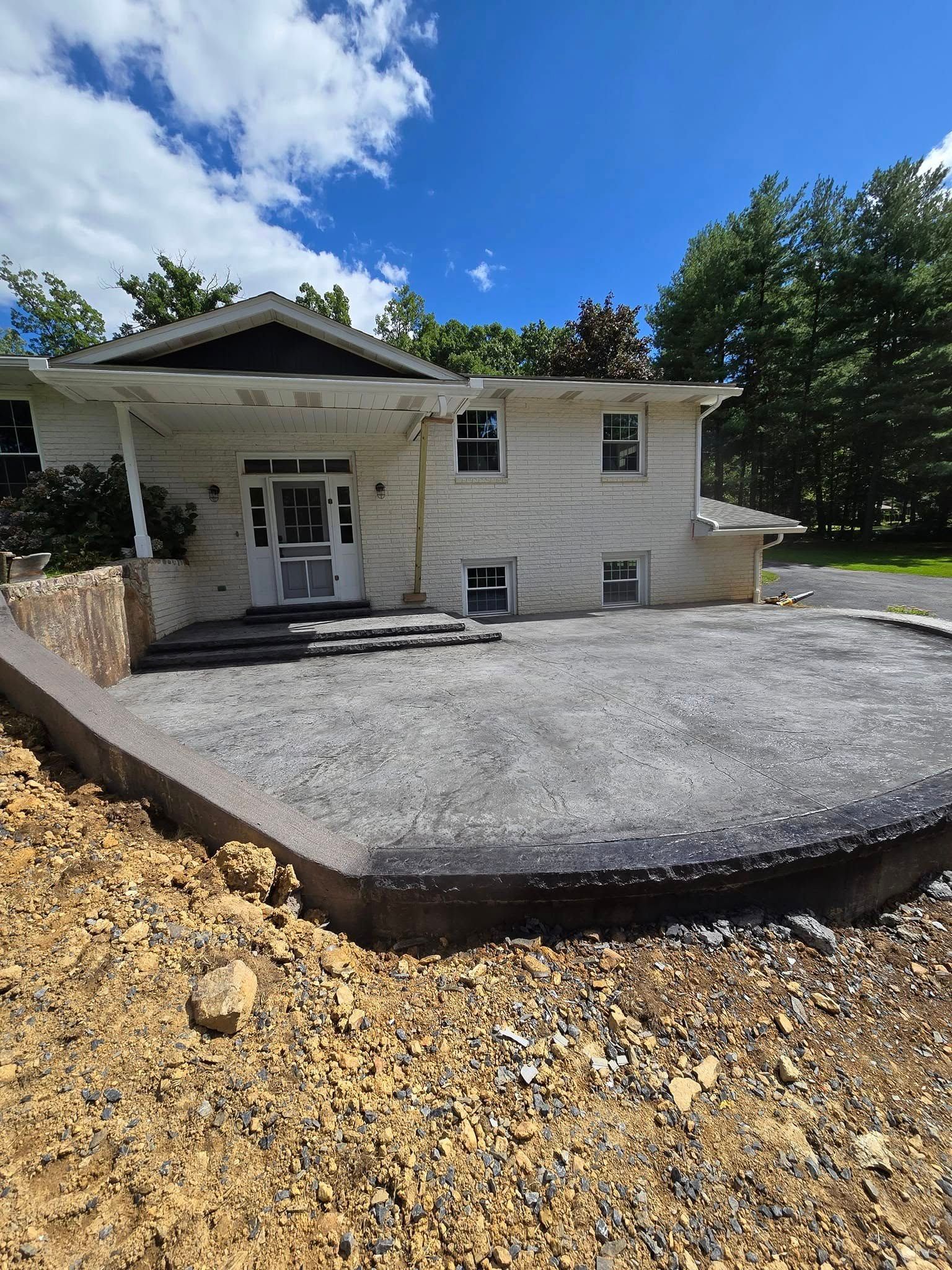 A white house with a gravel driveway in front of it.
