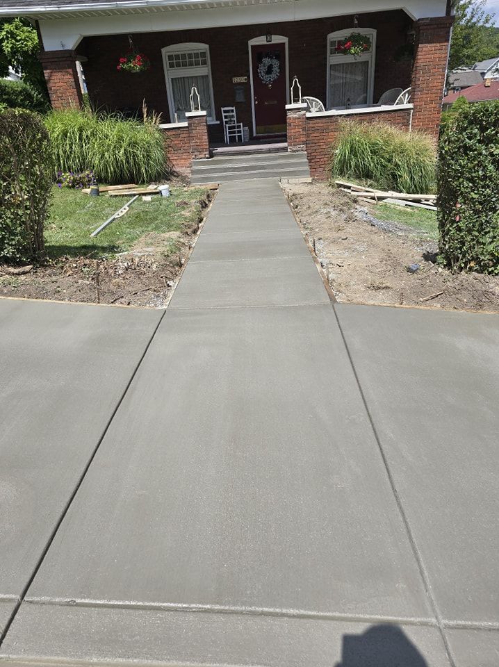 A concrete walkway leading to a brick house.