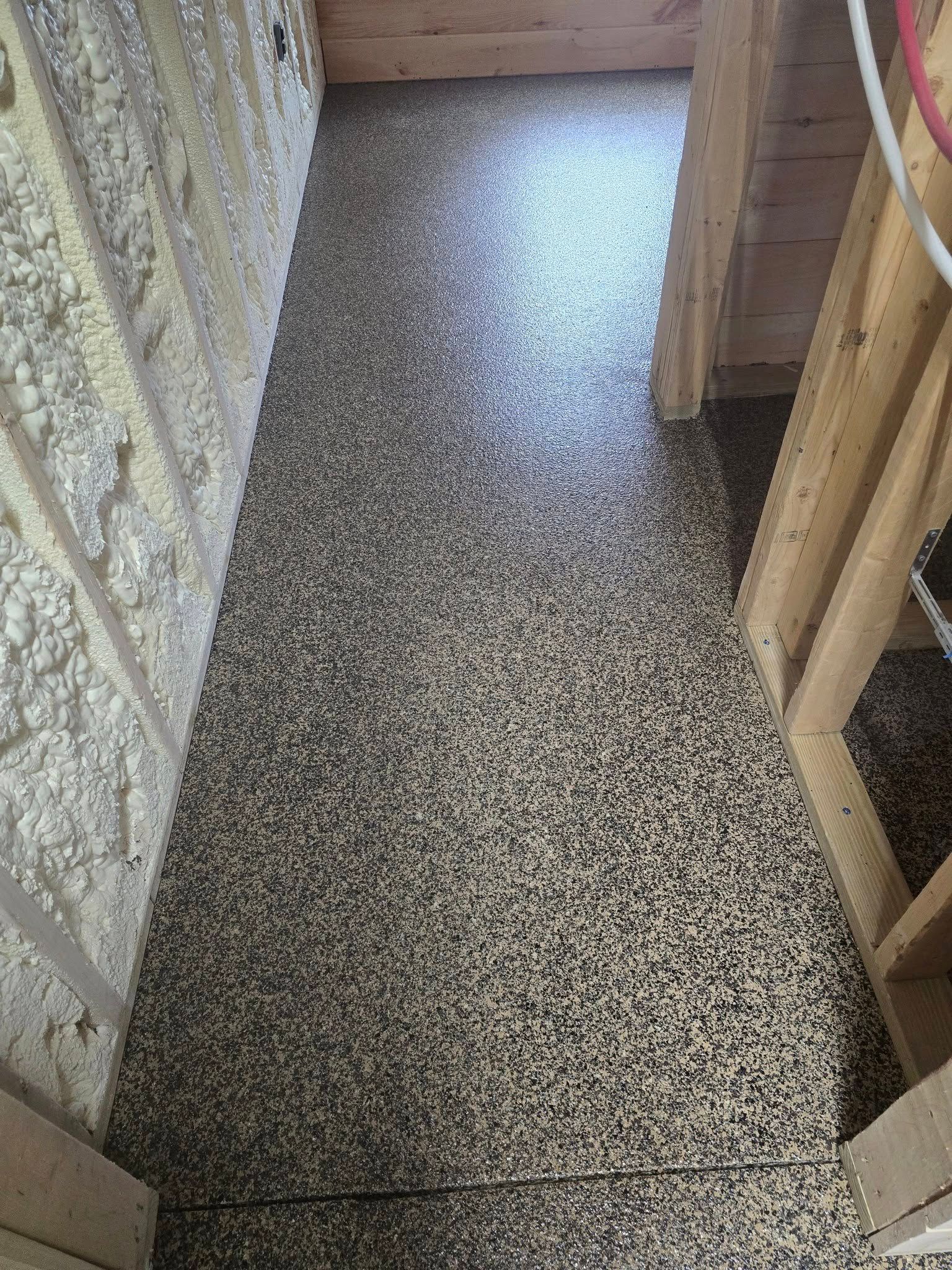 A hallway with a concrete floor and a wooden wall.