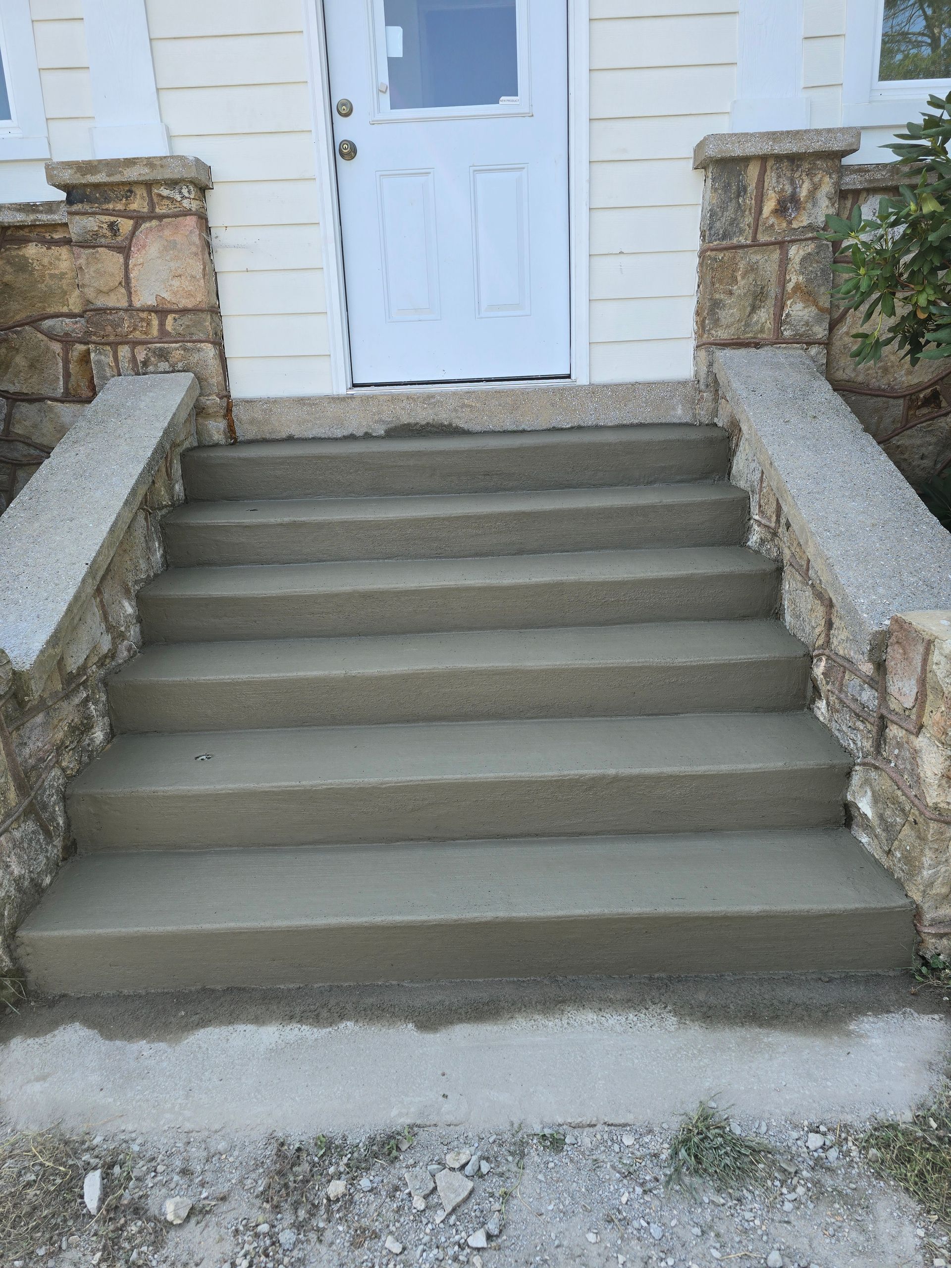 A set of concrete steps leading up to a white door.
