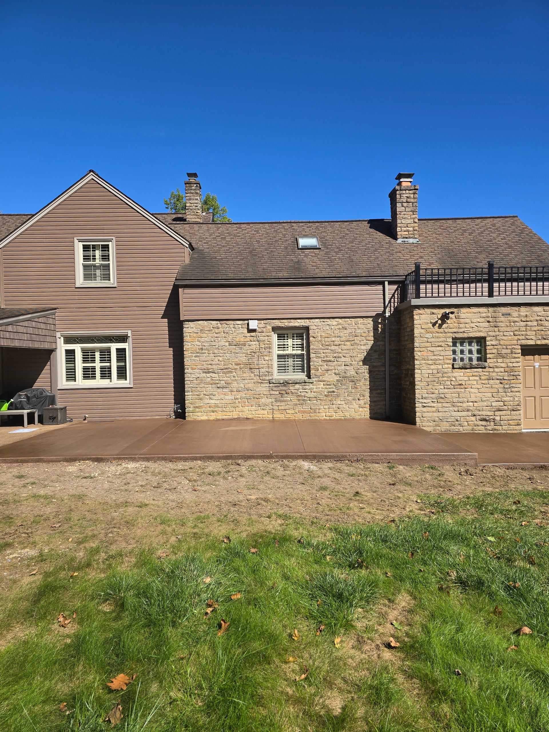 A large house with a lot of windows is sitting in the middle of a grassy field.