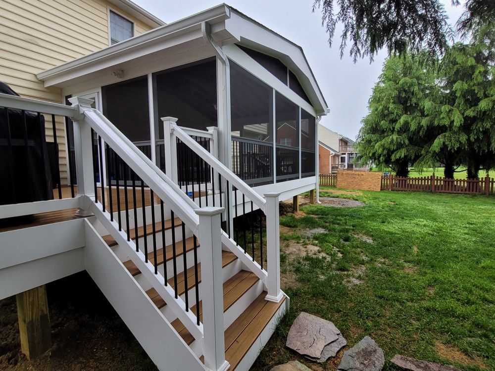 White porch stairs with railings leading to a screened backyard patio beside a house