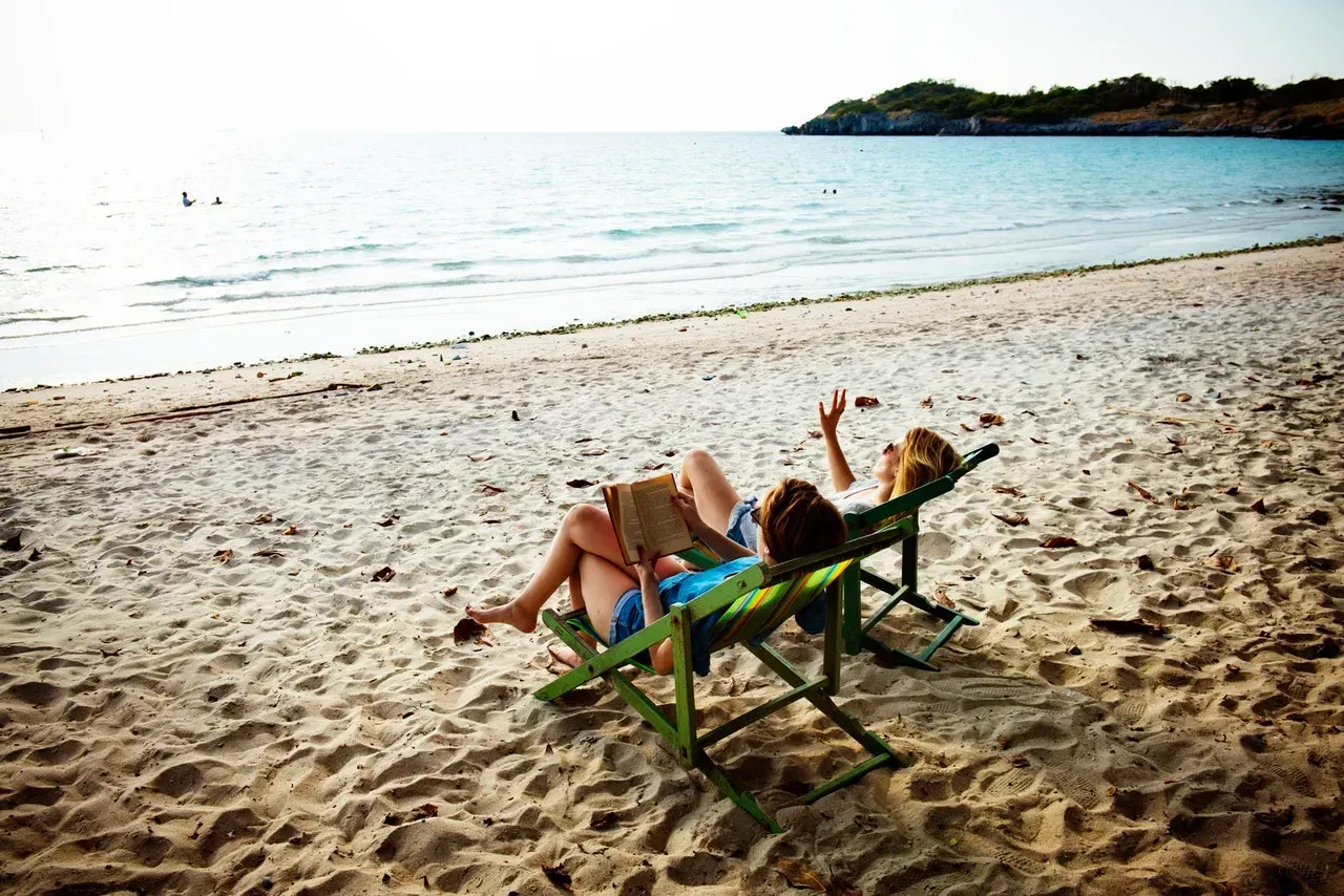 Two people lounging on beach chairs on a sandy beach by the sea