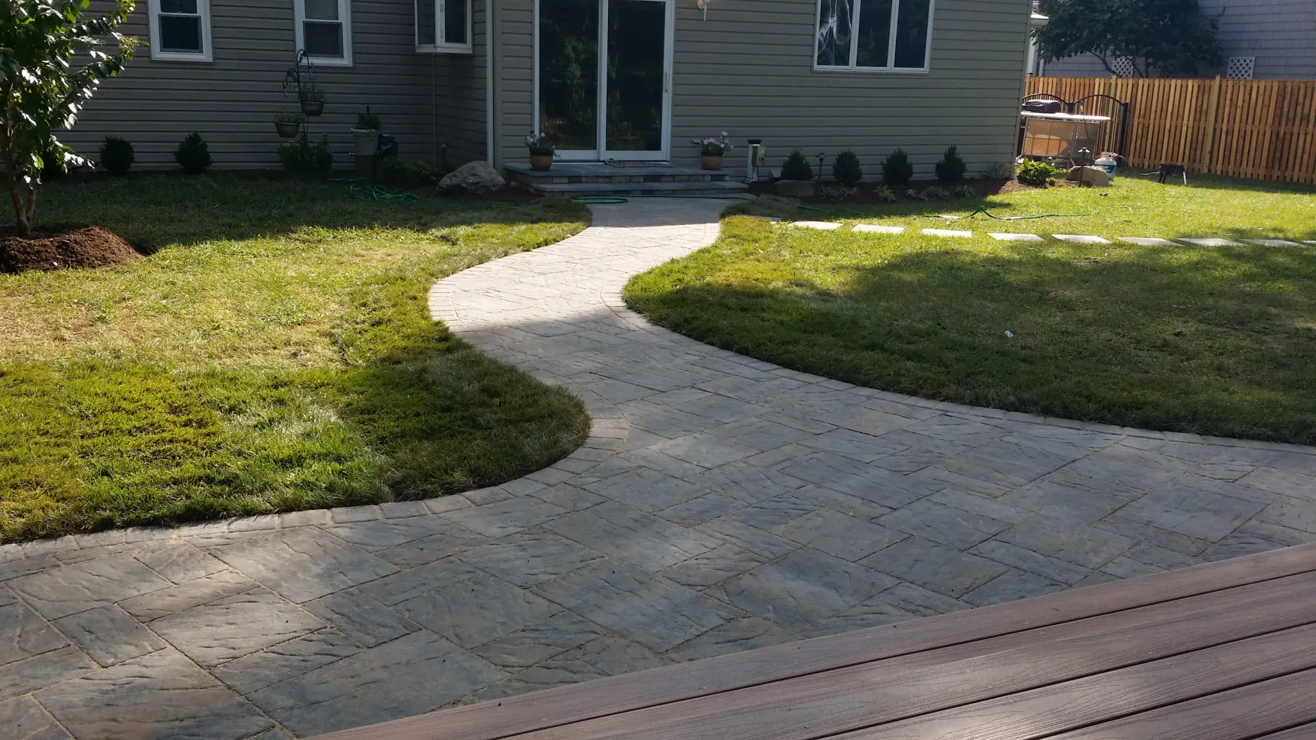 Curved concrete walkway leading to a house entrance across a green lawn