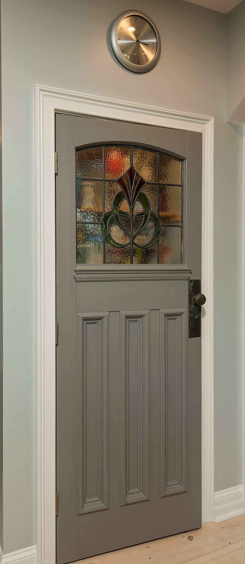 Gray front door with stained-glass window in a beige entryway
