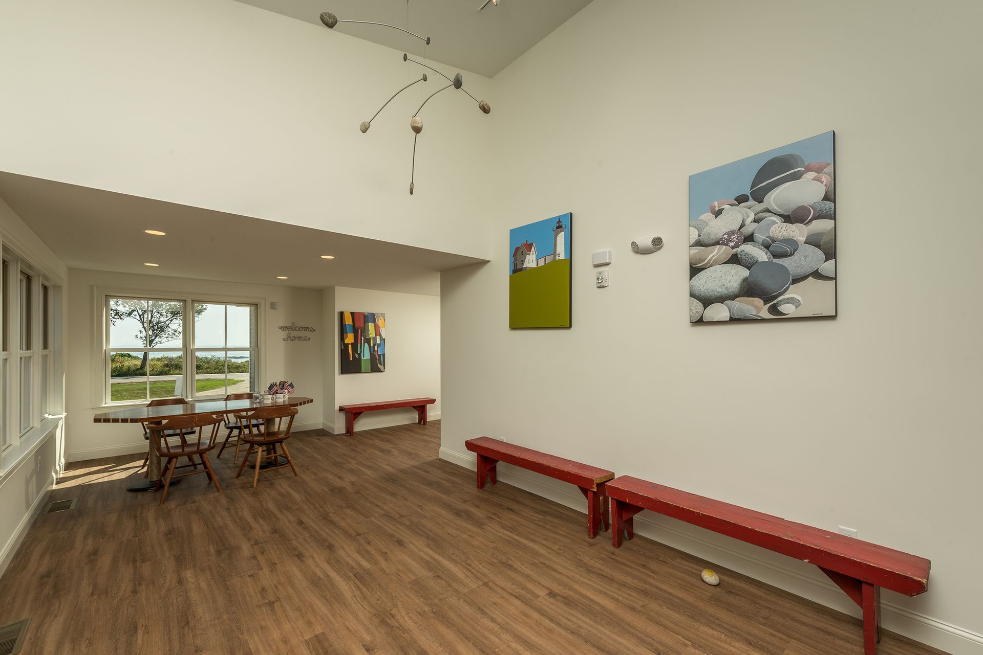 Bright gallery room with wood floors, red benches, and abstract wall art.