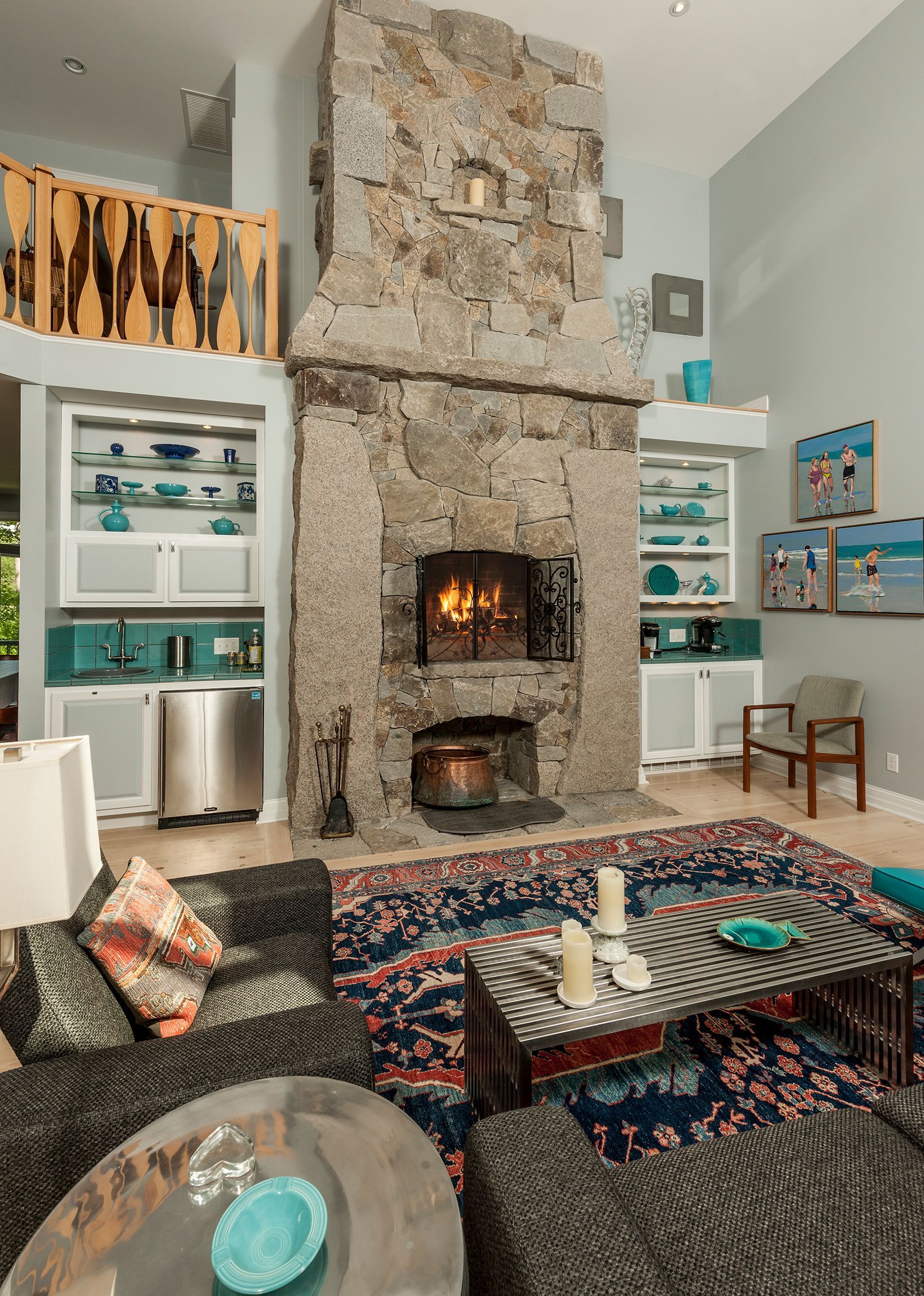 Cozy living room with a stone fireplace, built-in shelves, and colorful patterned rugs and cushions