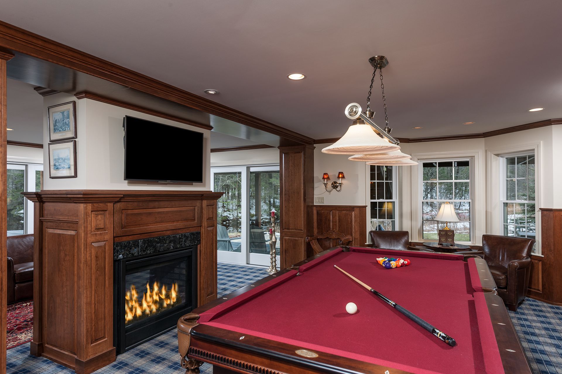 Game room with pool table, lit fireplace, and large windows