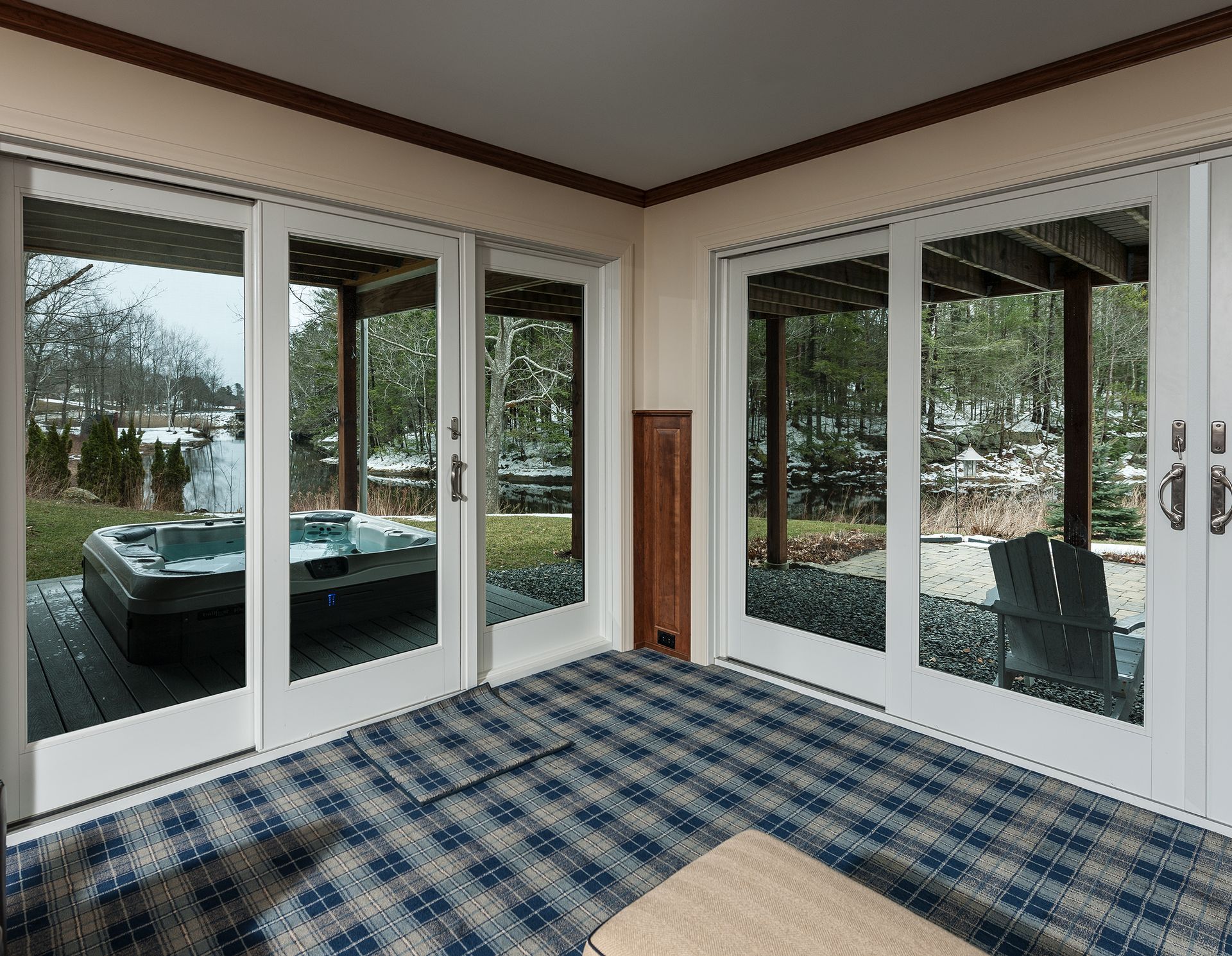 Sunroom with plaid carpet, sliding glass doors, and a hot tub visible outside
