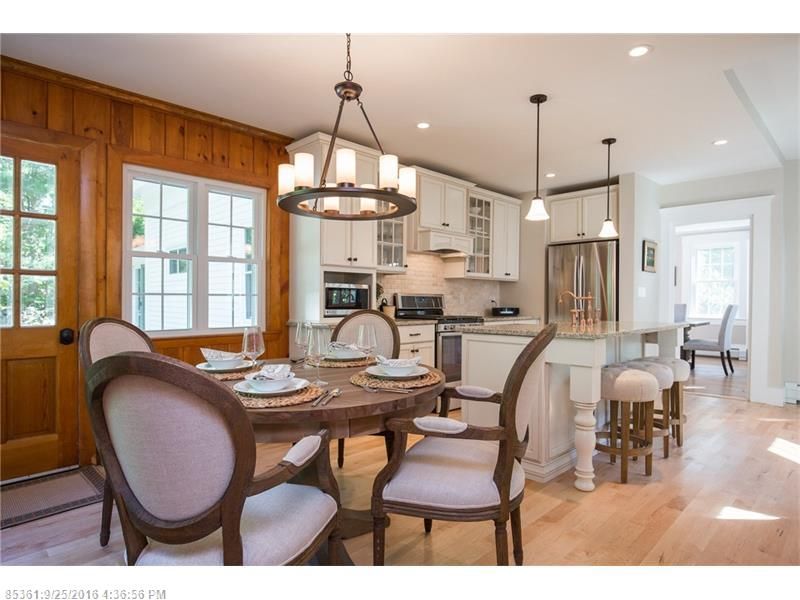 Bright kitchen and dining area with wood cabinets, round table, and island under pendant lights