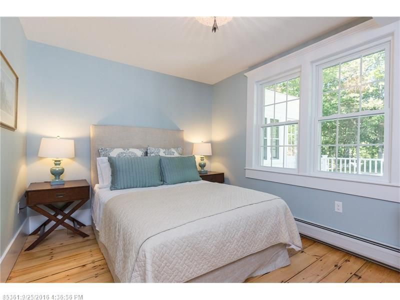 Bright bedroom with a bed, blue walls, white windows, and bedside lamps