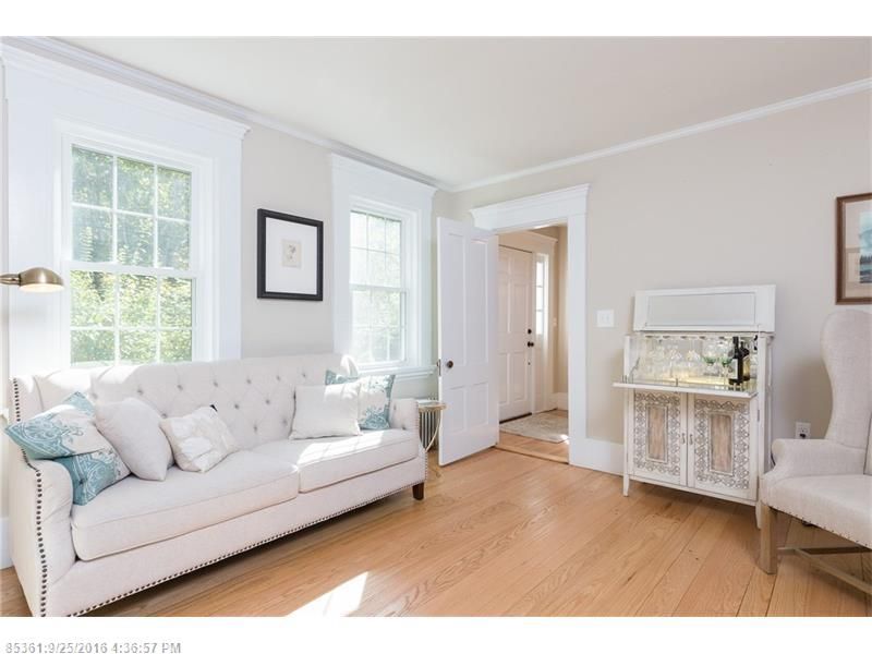 Bright white living room with sofa, chair, framed art, and hardwood floors