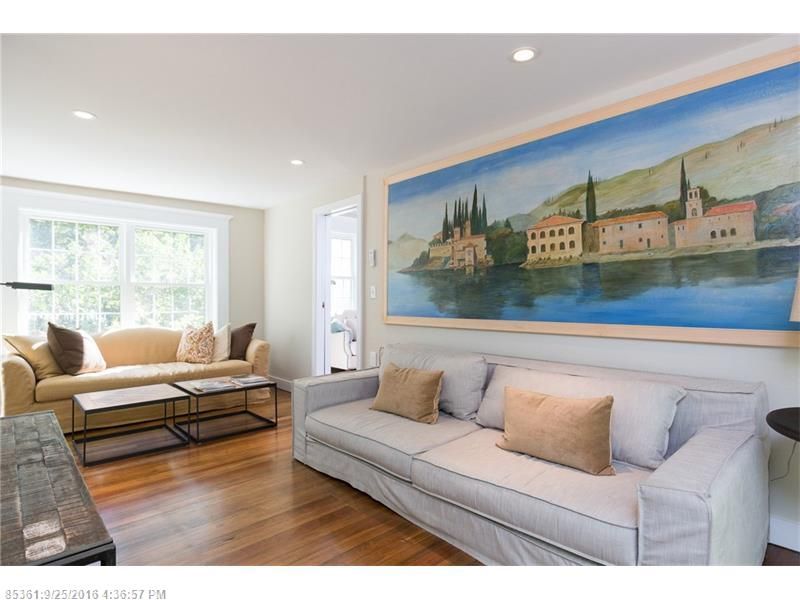 Bright living room with gray sofa, tan chaise, and large colorful landscape painting above the couch