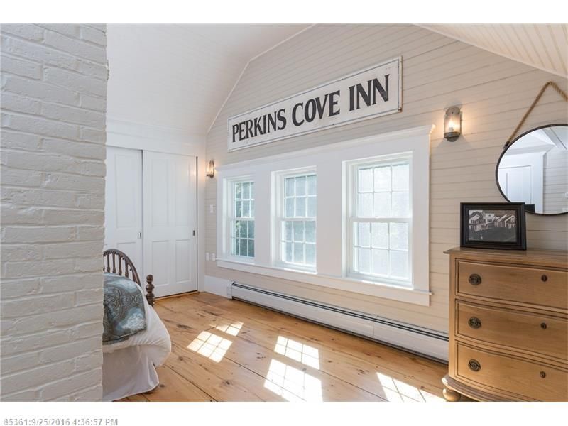 Bright inn foyer with white walls, wood floor, and “Perkins Cove Inn” sign above windows
