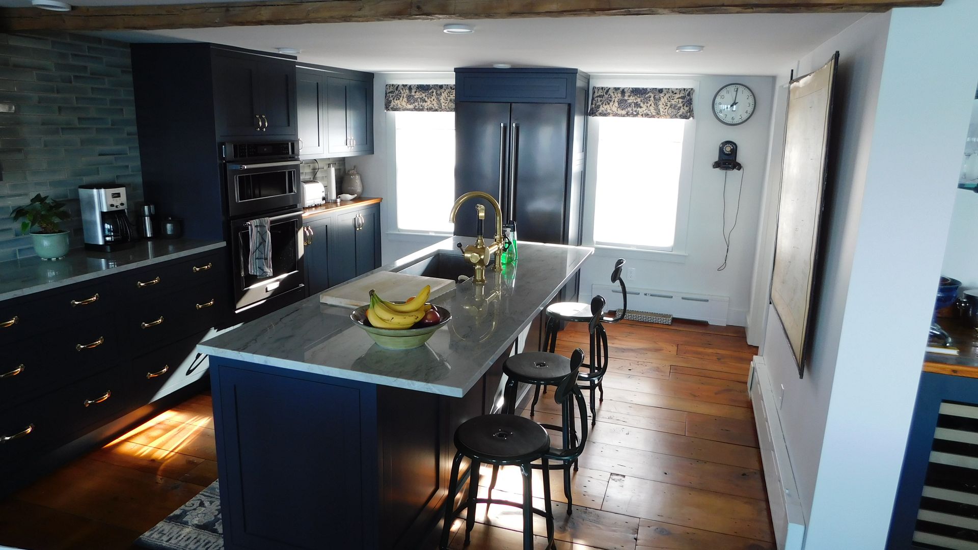 Modern kitchen with dark cabinets, central island, and fruit bowl by a bright window