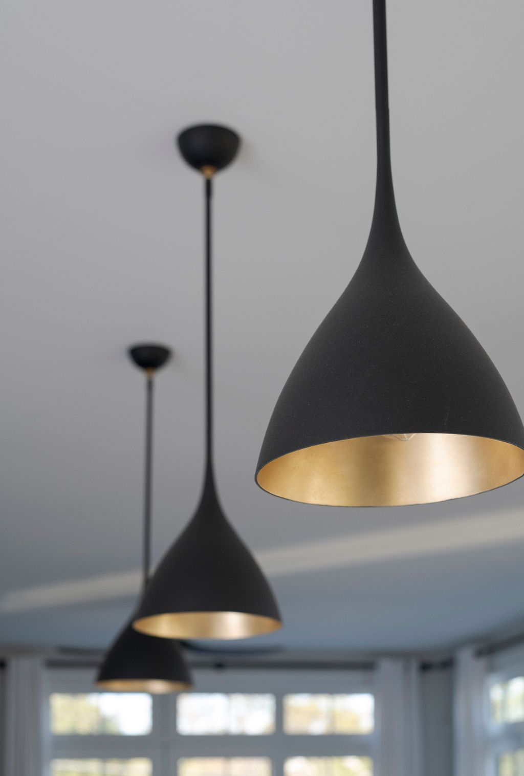 Black pendant lights with gold interiors hanging in a modern room