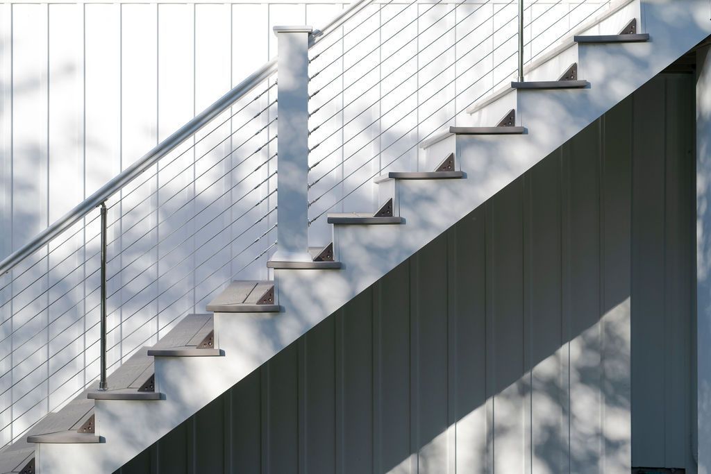 Exterior staircase with metal railings and a white cable fence on a modern building