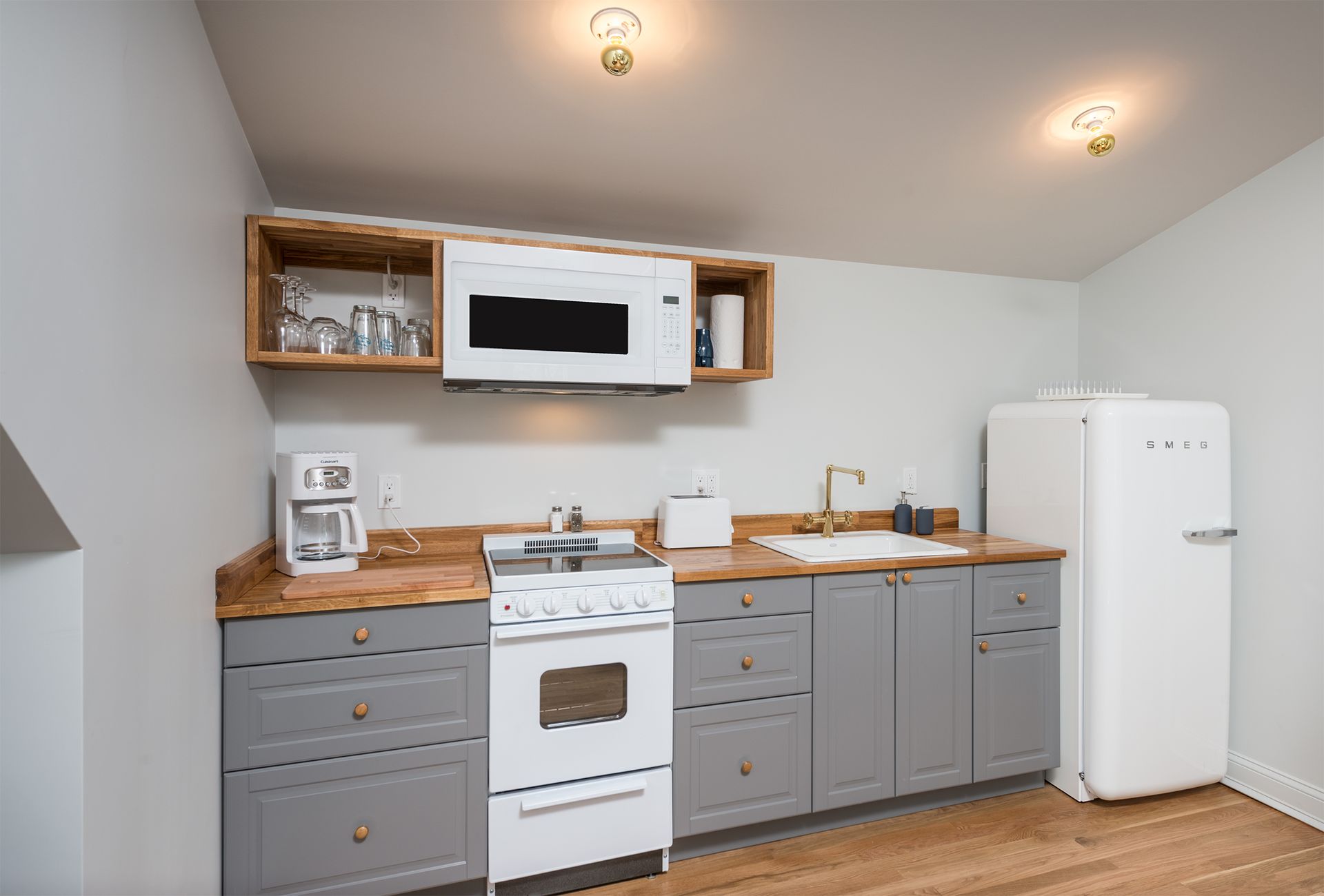 Small kitchen with gray cabinets, white appliances, wooden countertops, and a white fridge.