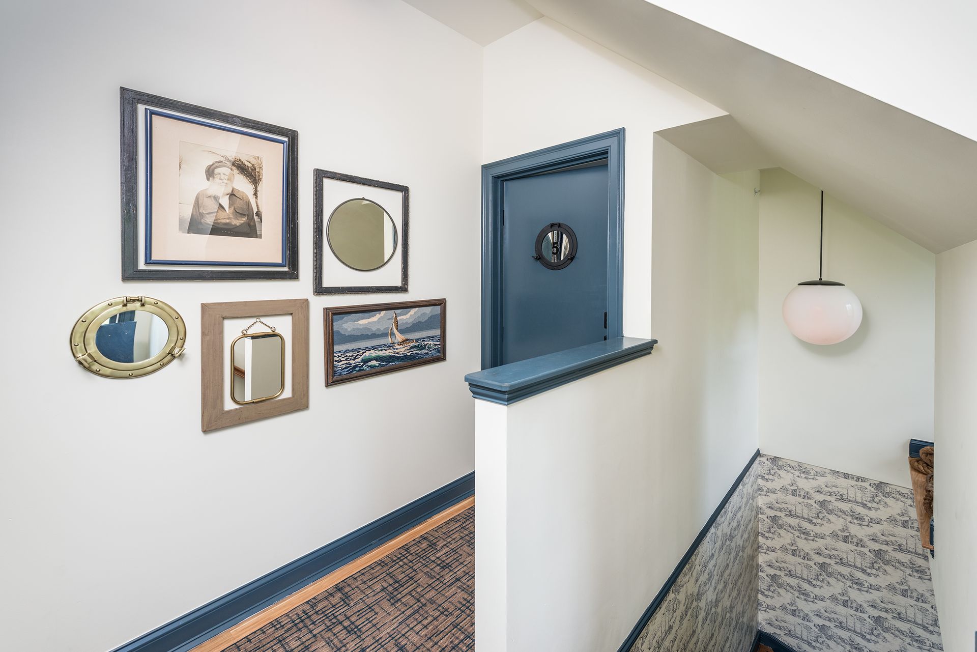 Hallway landing with framed wall art, blue accent nook, and a hanging globe lamp
