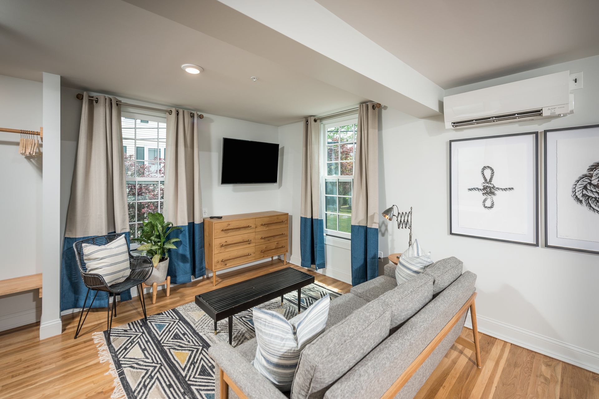 Modern living room with gray sofa, wall-mounted TV, patterned rug, and blue accent curtains