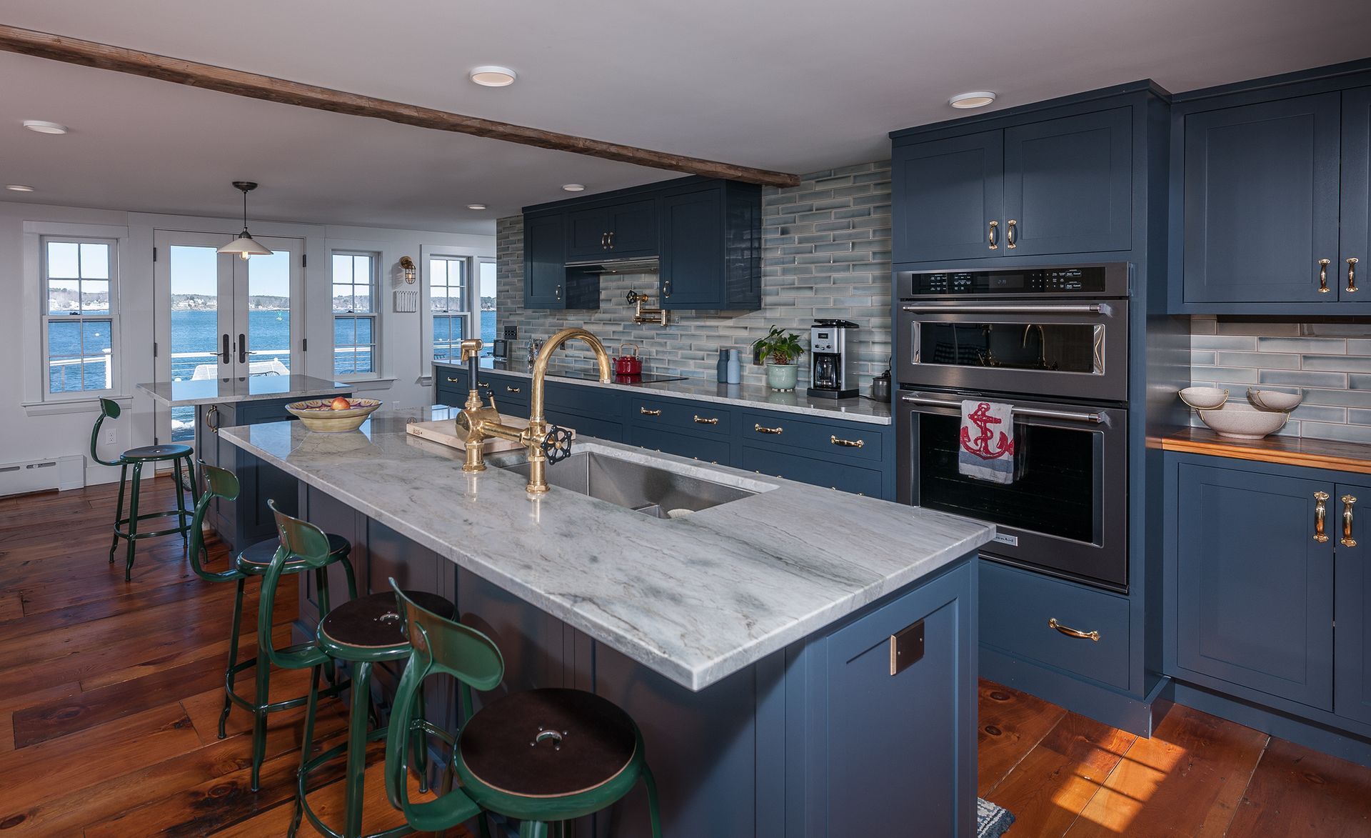 Modern kitchen with blue cabinets, marble island, and bar stools in a bright open-plan room