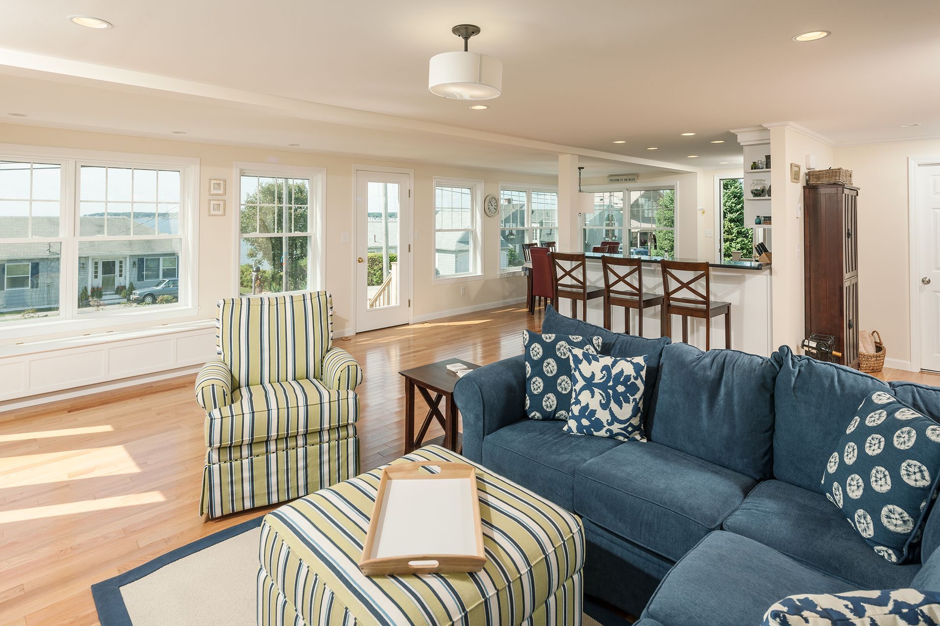 Bright living room with blue sofa, striped chair, and large windows overlooking water