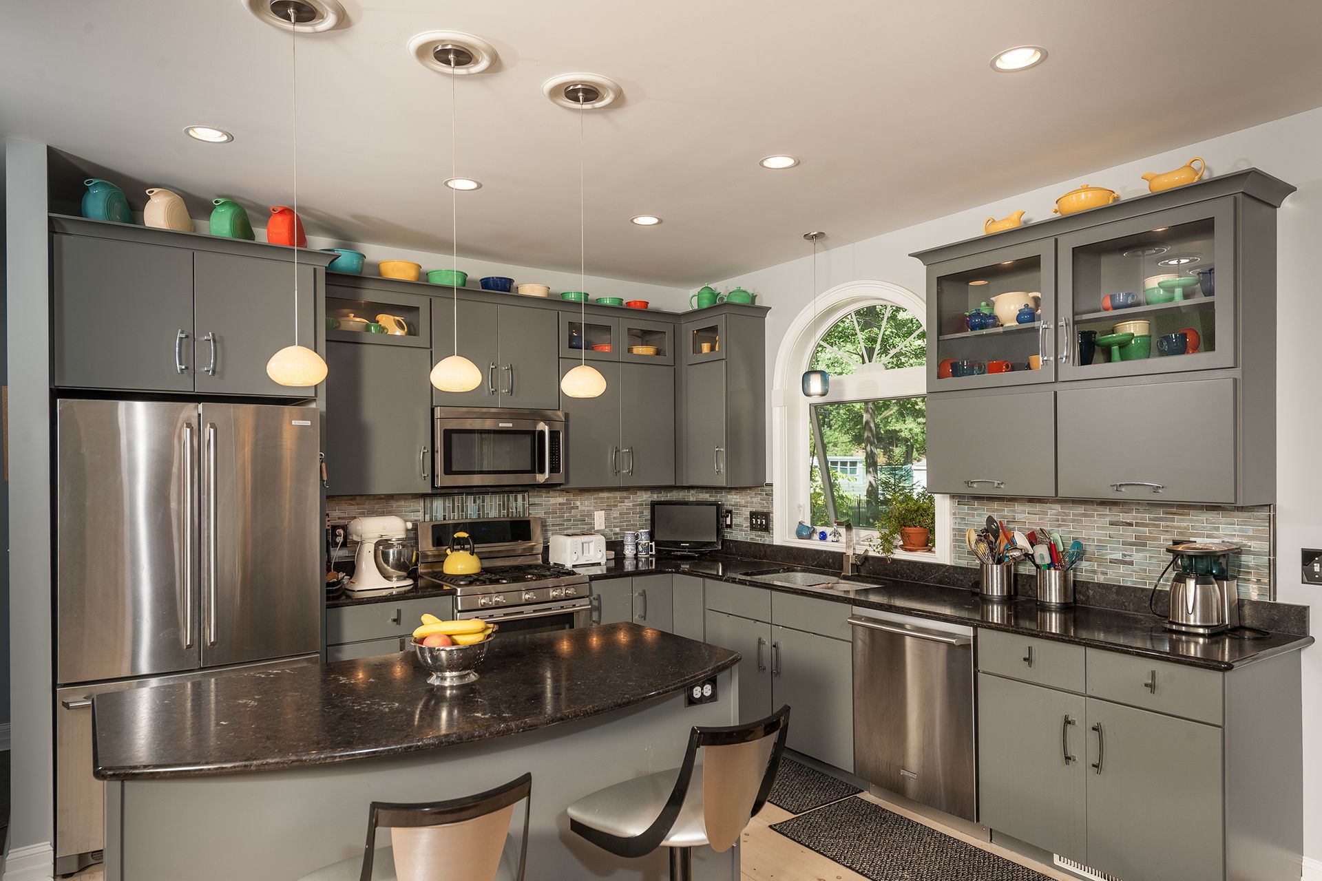 Modern kitchen with gray cabinets, stainless steel appliances, and dark granite counters