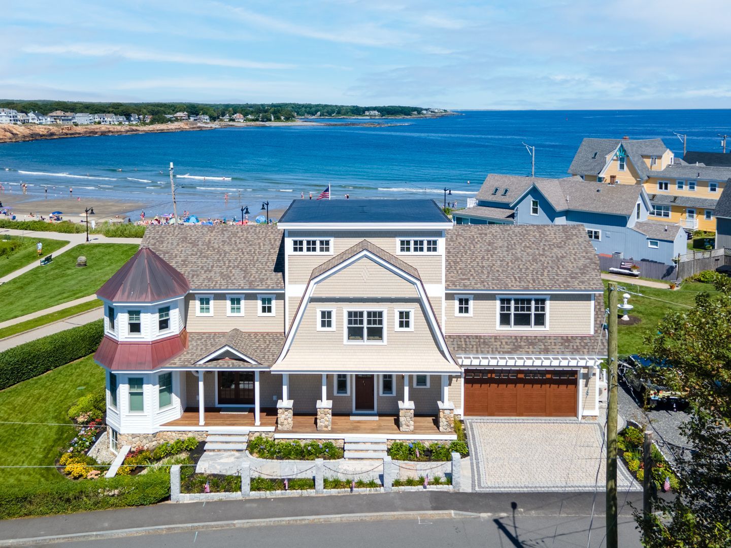Coastal house with gray roof and white trim overlooking a blue bay and shoreline