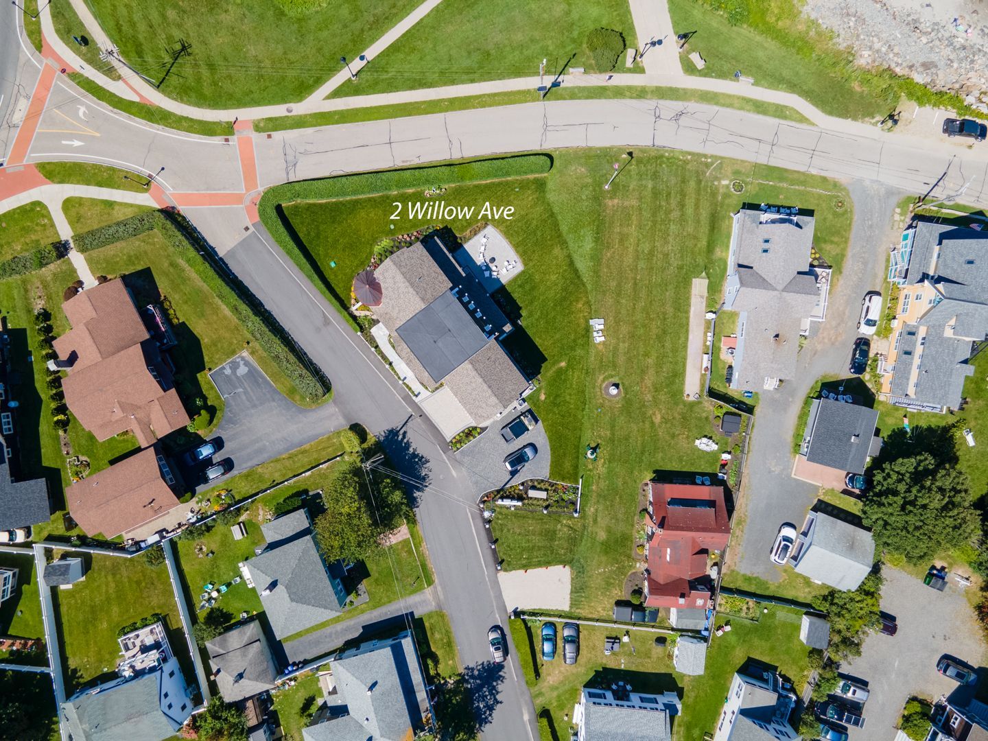 Aerial view of suburban homes, lawns, and roads around a curved street intersection.