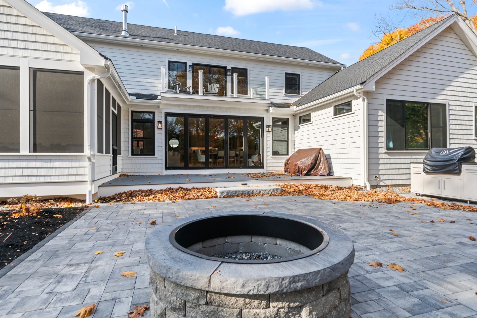 Backyard patio with stone fire pit, paved seating area, and a modern house exterior with large windows