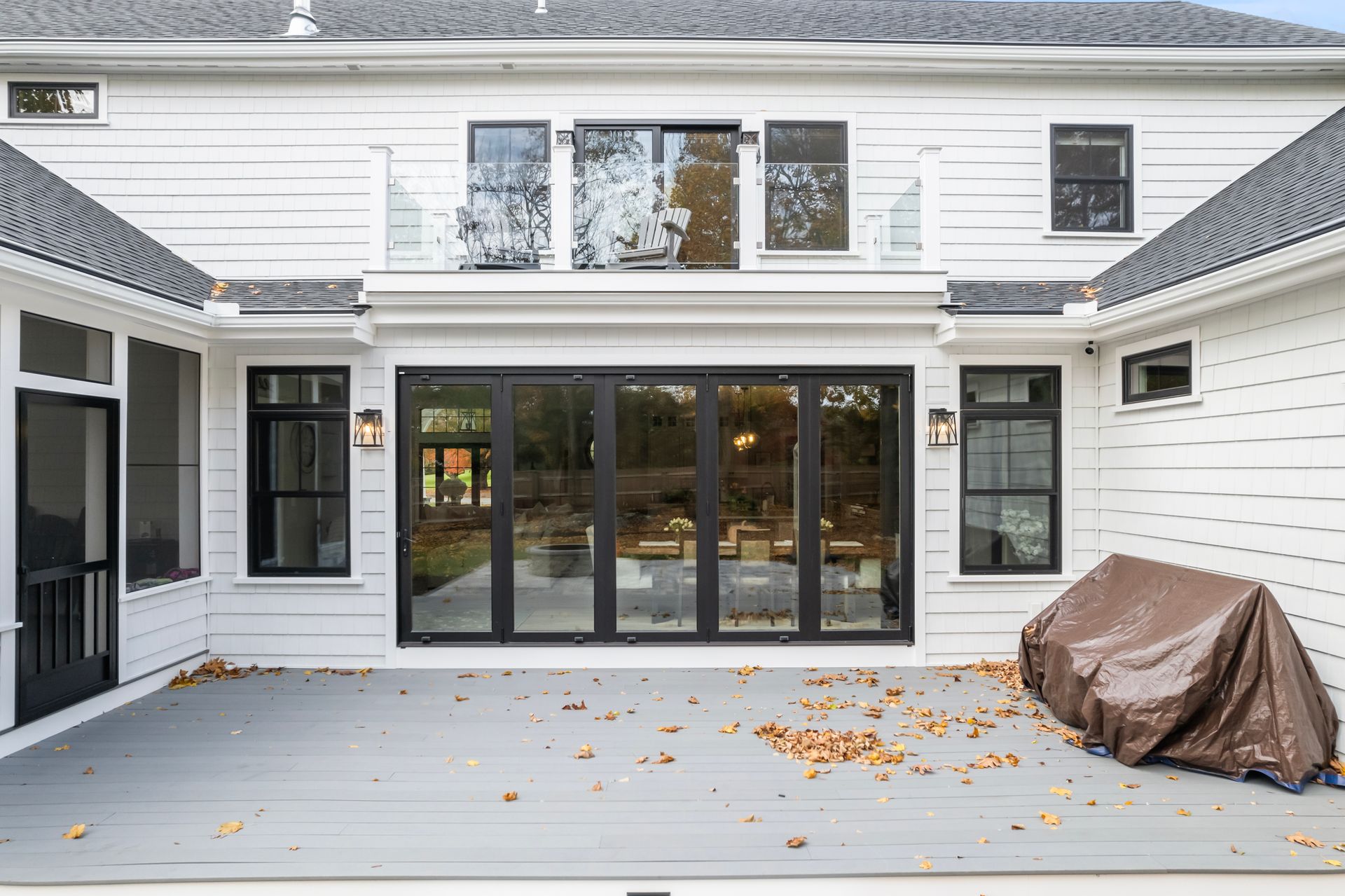 White house patio with large black-framed sliding doors and a covered item on the right