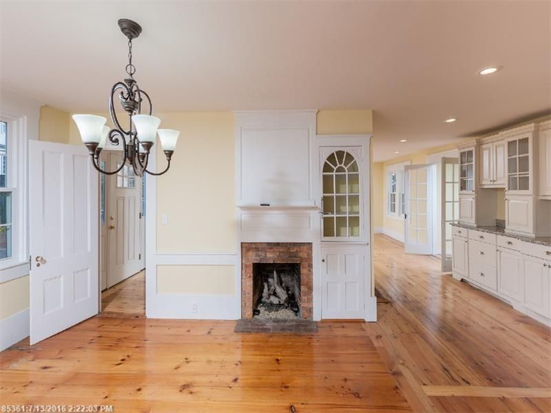Bright kitchen with white cabinets, hardwood floors, and a small fireplace with built-in shelving.