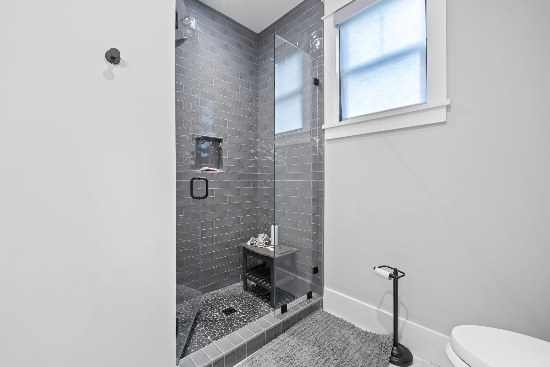 Small tiled walk-in shower with glass door and white bathroom walls