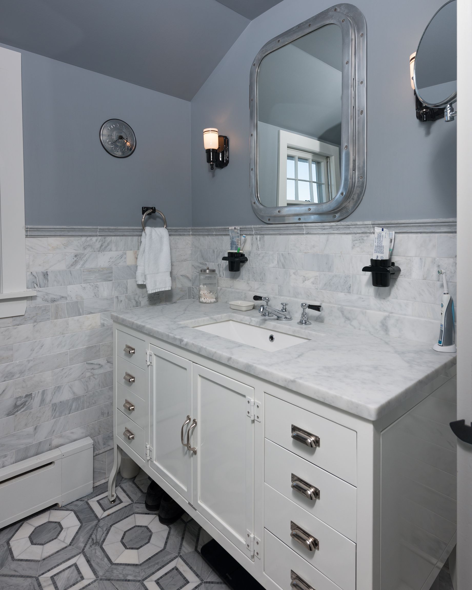 Modern white bathroom with marble vanity, hexagon tile floor, mirror, and gray-blue walls