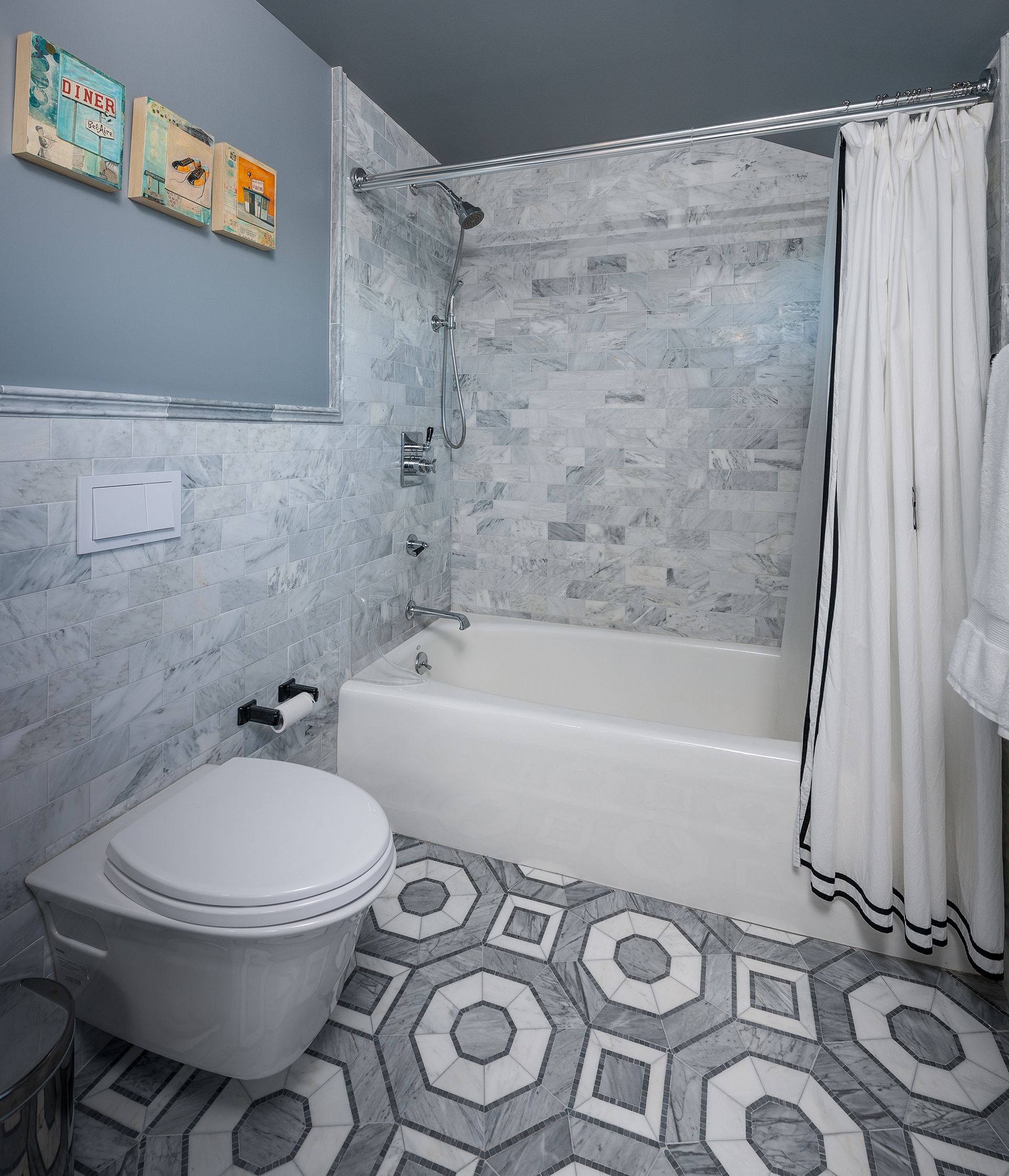 Small bathroom with hexagon tile floor, tub-shower, toilet, and white shower curtain.