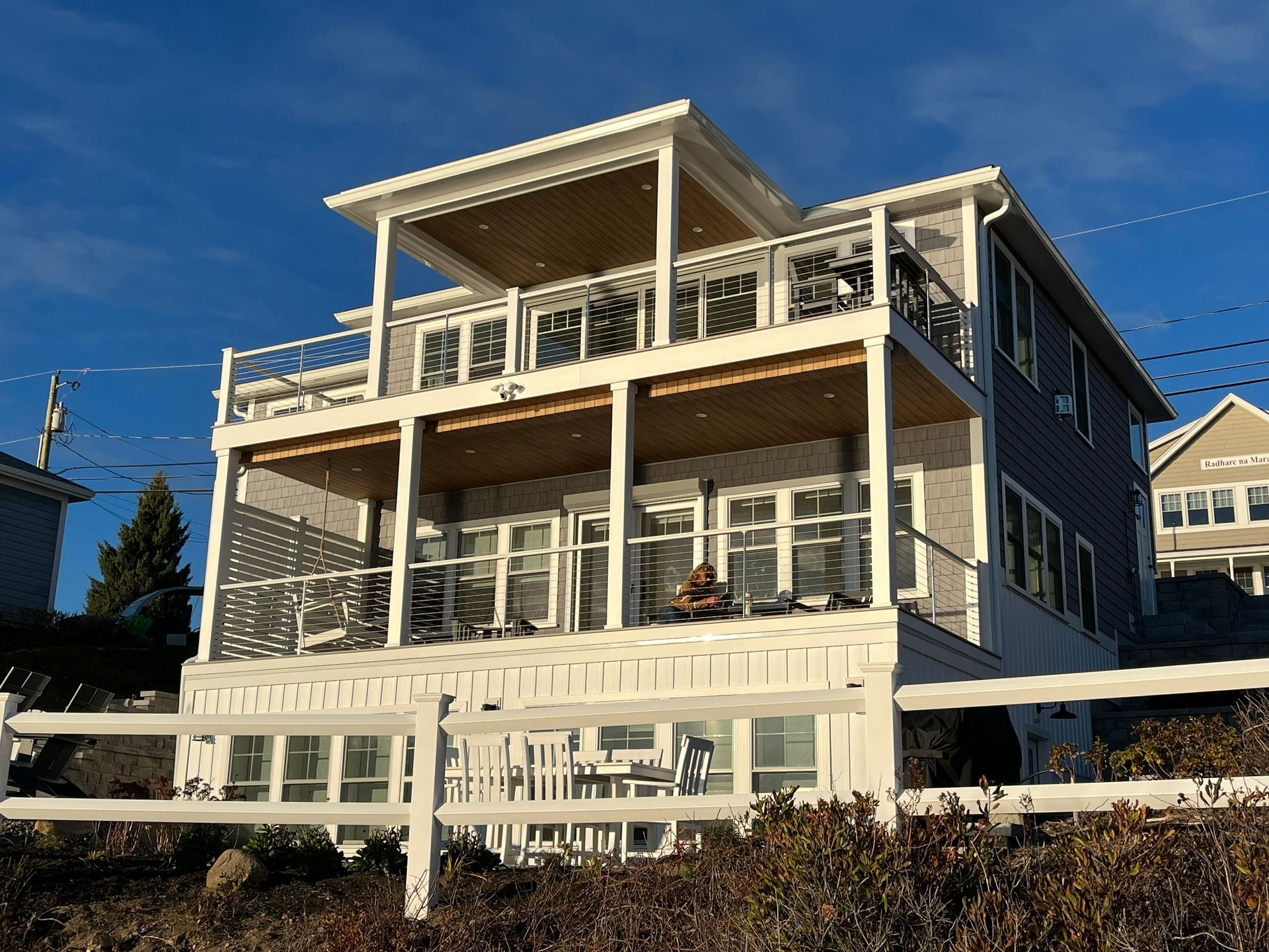 Beachfront house with a large white porch and railings under a clear blue sky