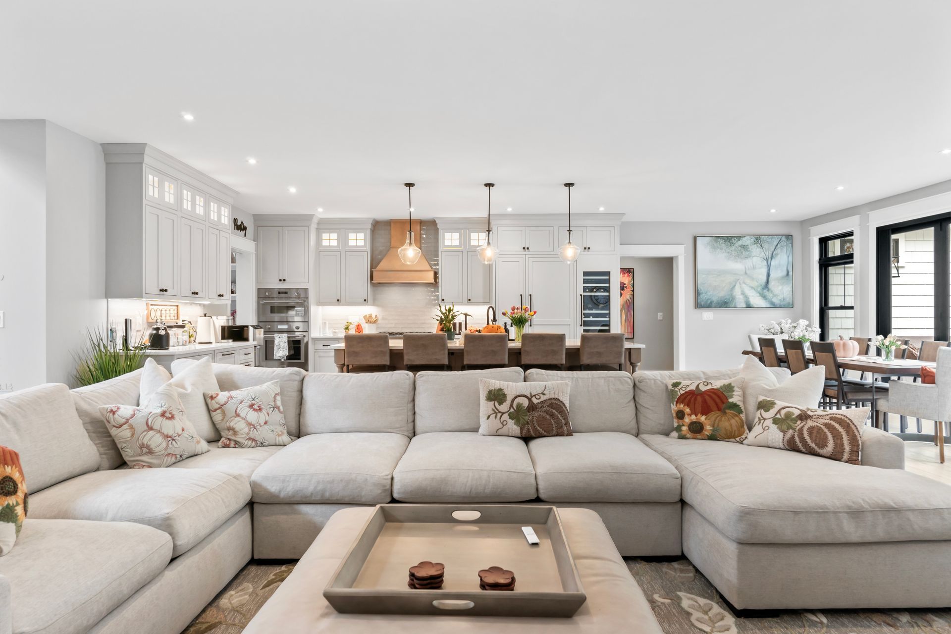Bright modern living room with a large white sectional, open kitchen, and dining area